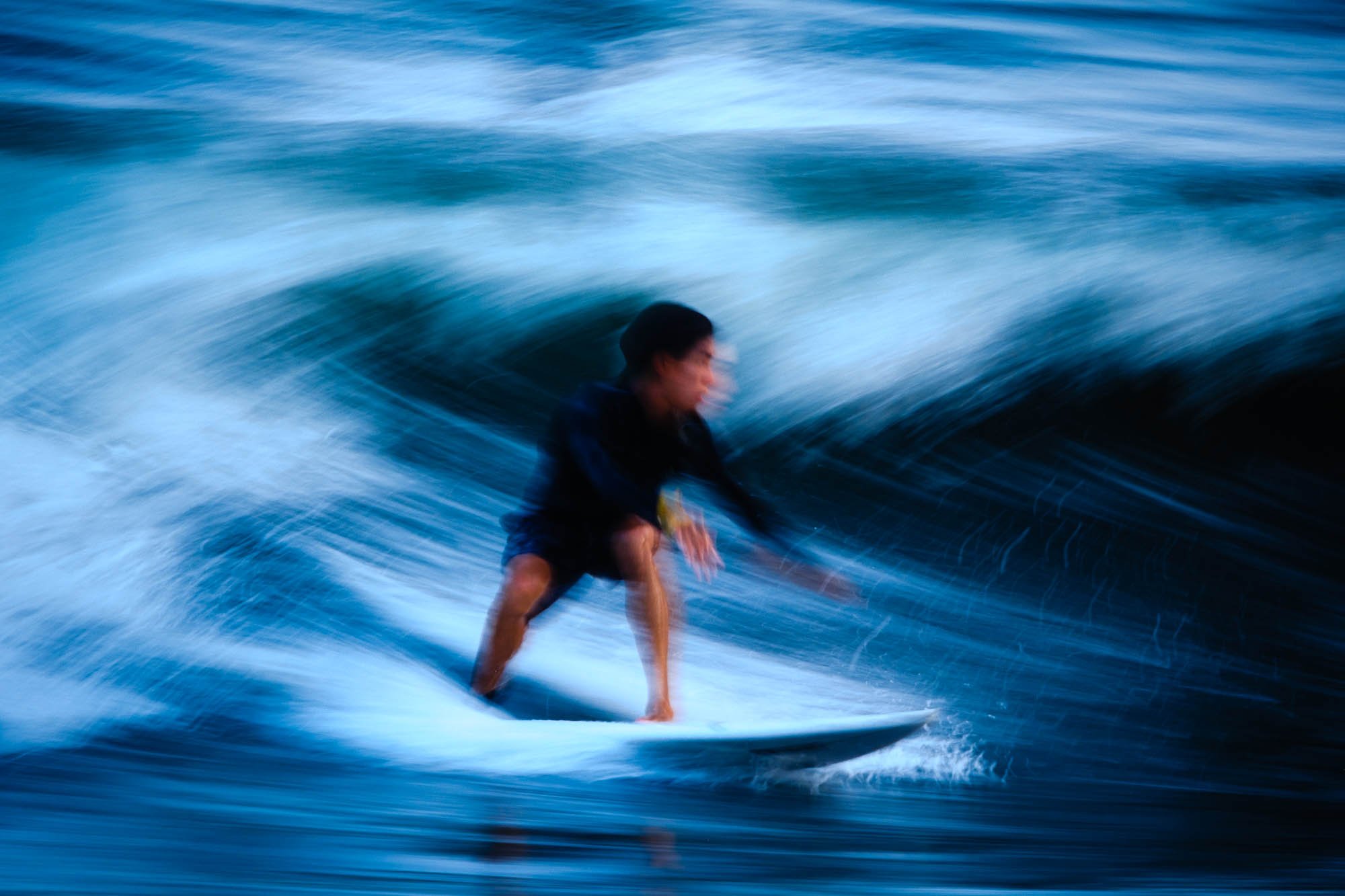 An image of a surfer riding a wave at Tsujido Beach, using a slow shutter speed and panning with the subject to show motion blur.