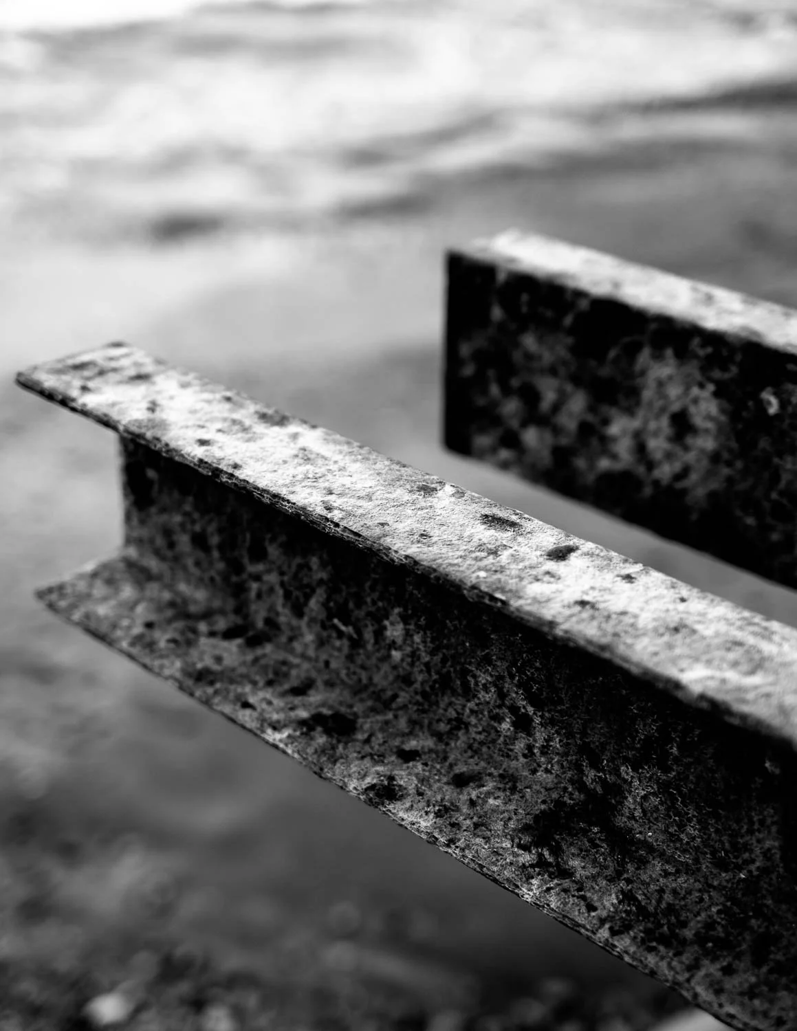  Abstract close-up of rusted metal beams above the waterline, captured in black and white along the coast of Kanagawa Prefecture. 