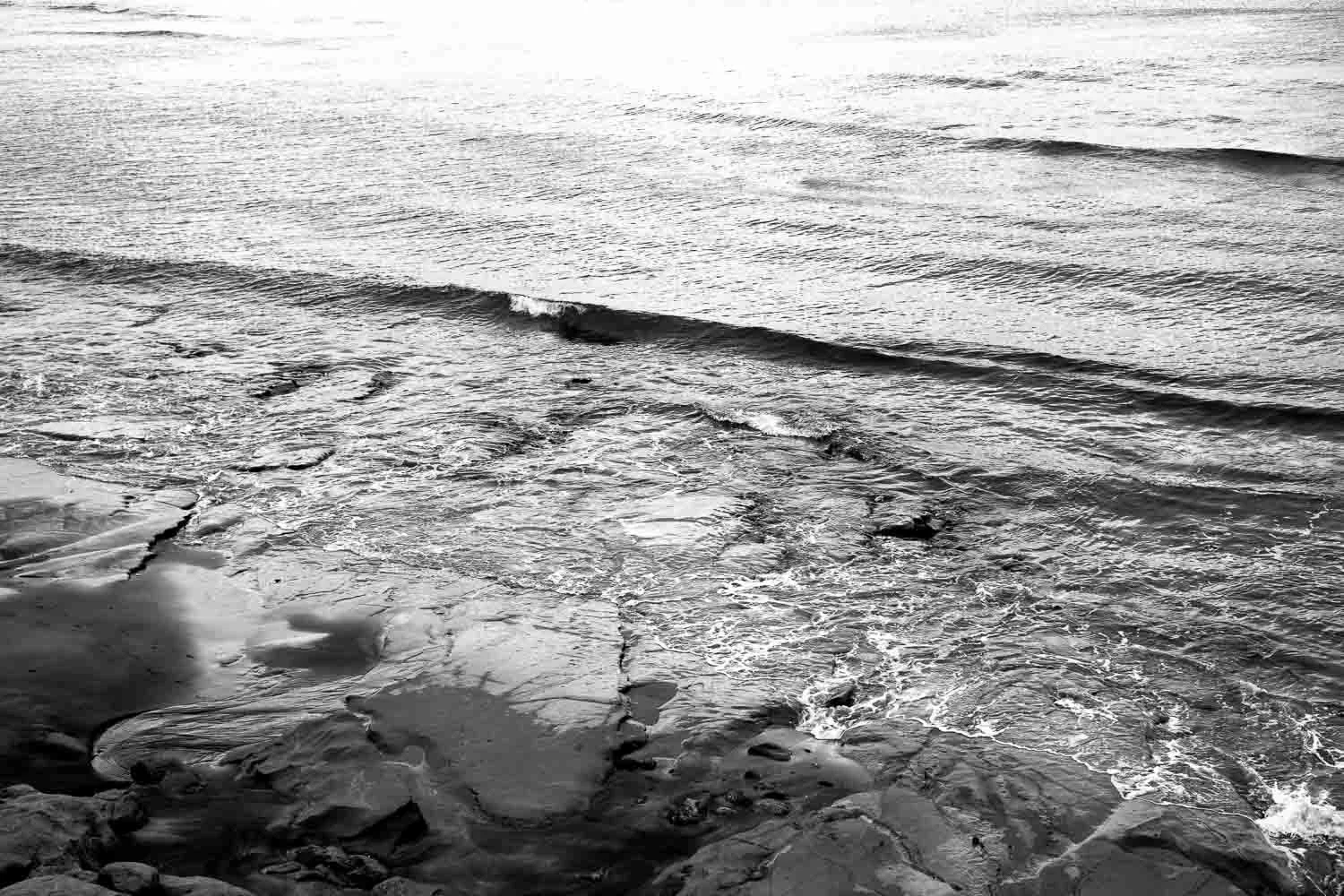 Black and white study of shallow waves rolling over rocks on the shoreline, part of a coastal photography series in Kanagawa Prefecture 