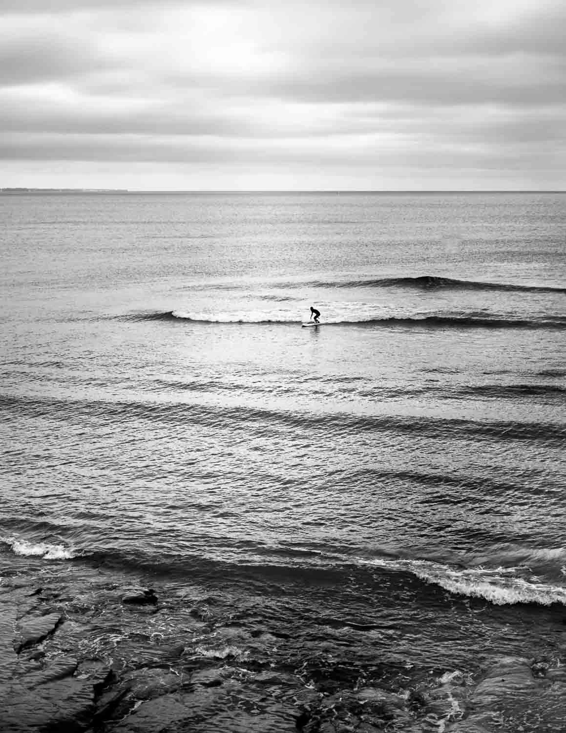  A lone surfer rides a small wave under heavy skies, captured in black and white by Japan travel photographer Ben Weller on the Shonan coast. 