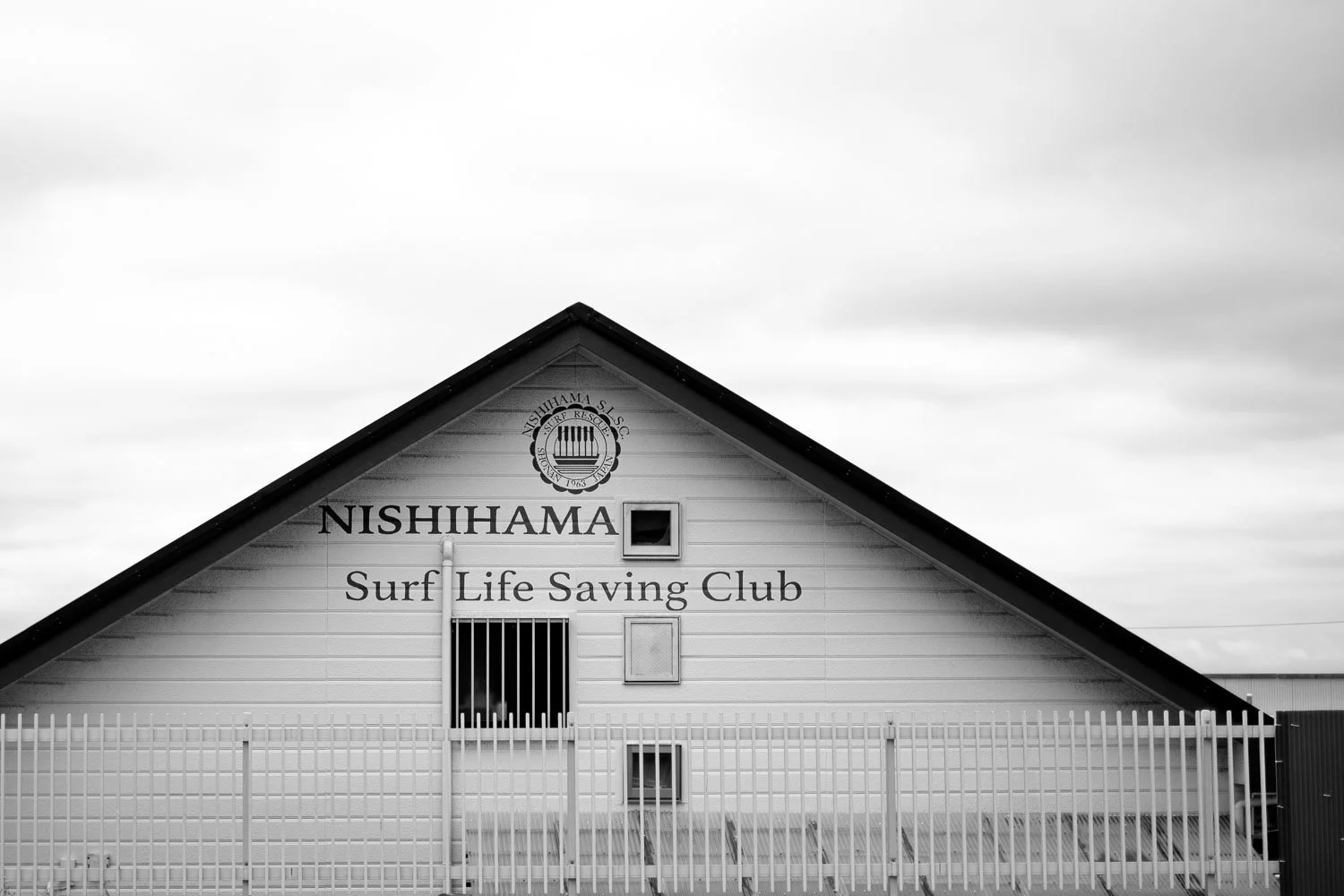  The Nishihama Surf Life Saving Club building in Fujisawa, its simple structure photographed in black and white as part of a coastal travel photography project in Japan. 
