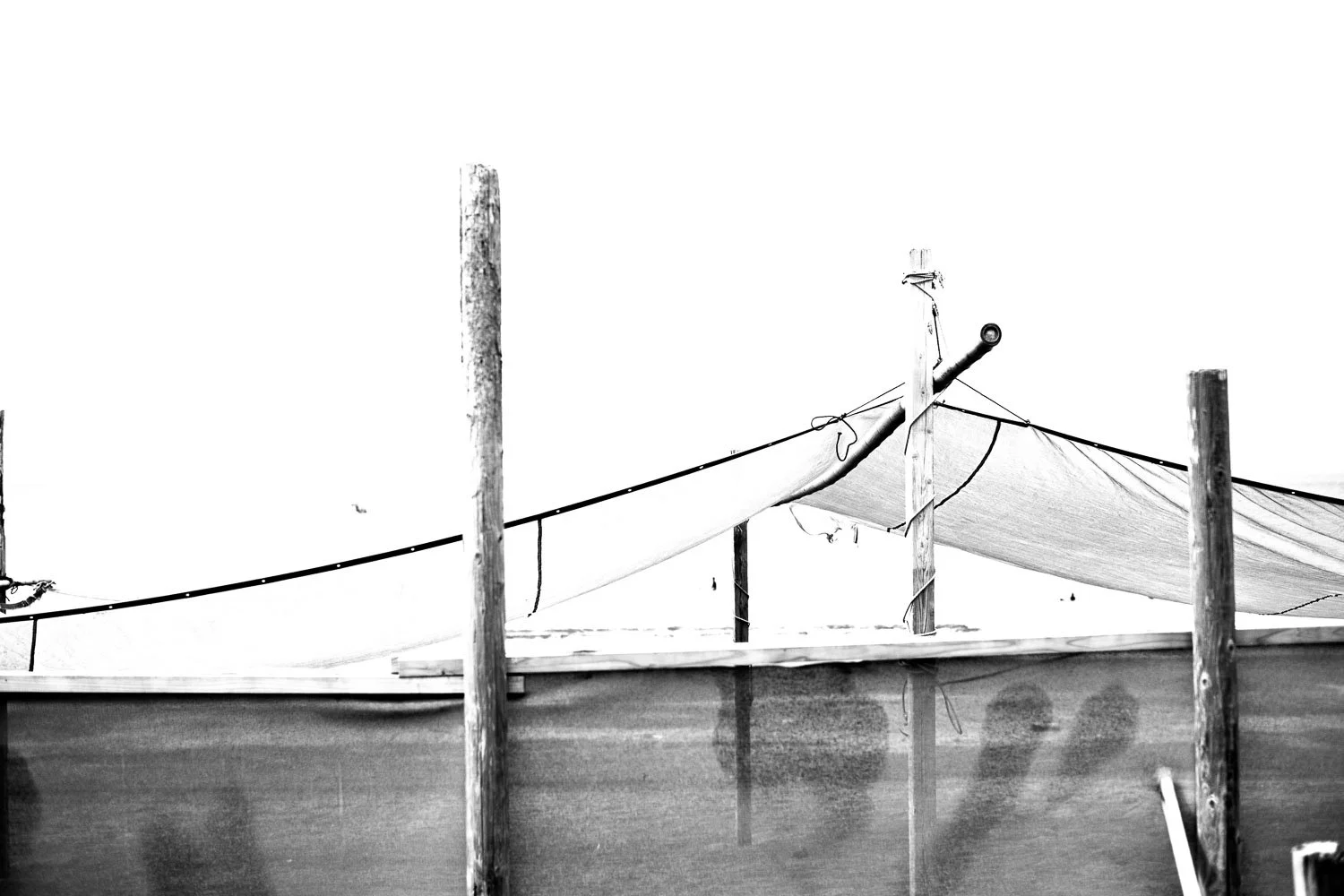  Canvas fishing shelter framed by wooden posts along the Shonan coast, captured in stark black and white. 