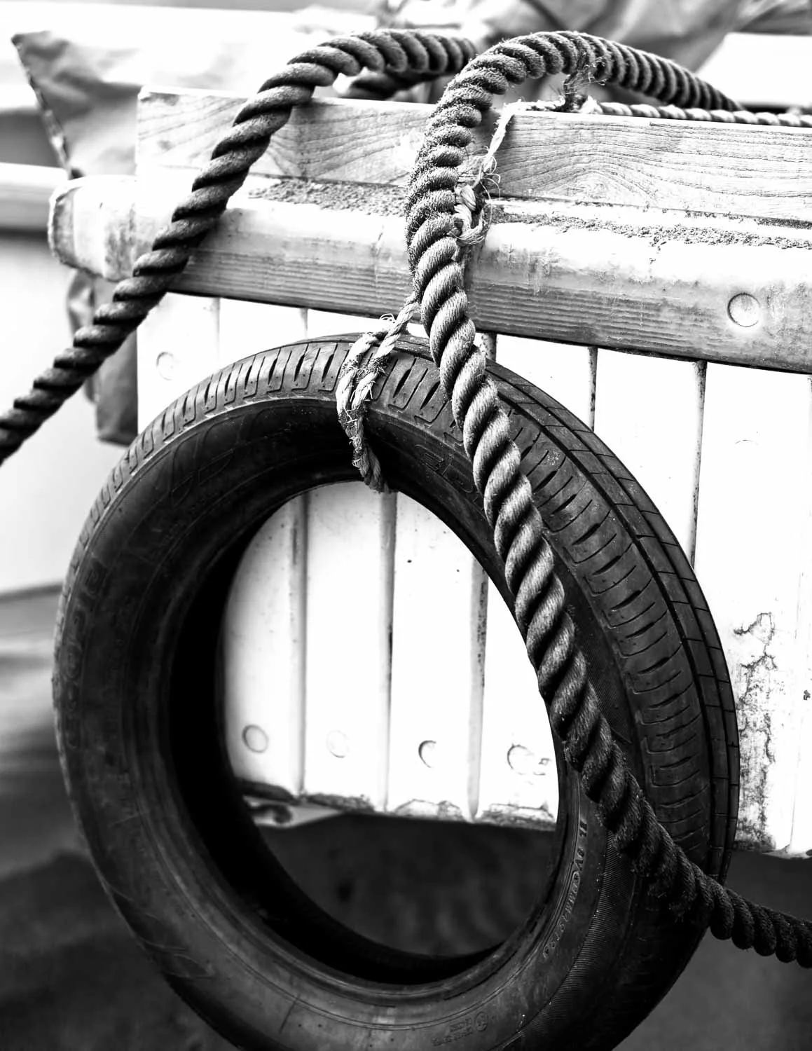 Detail of a mooring rope looped around an old tire, photographed in black and white along the Shonan coast of Japan. 
