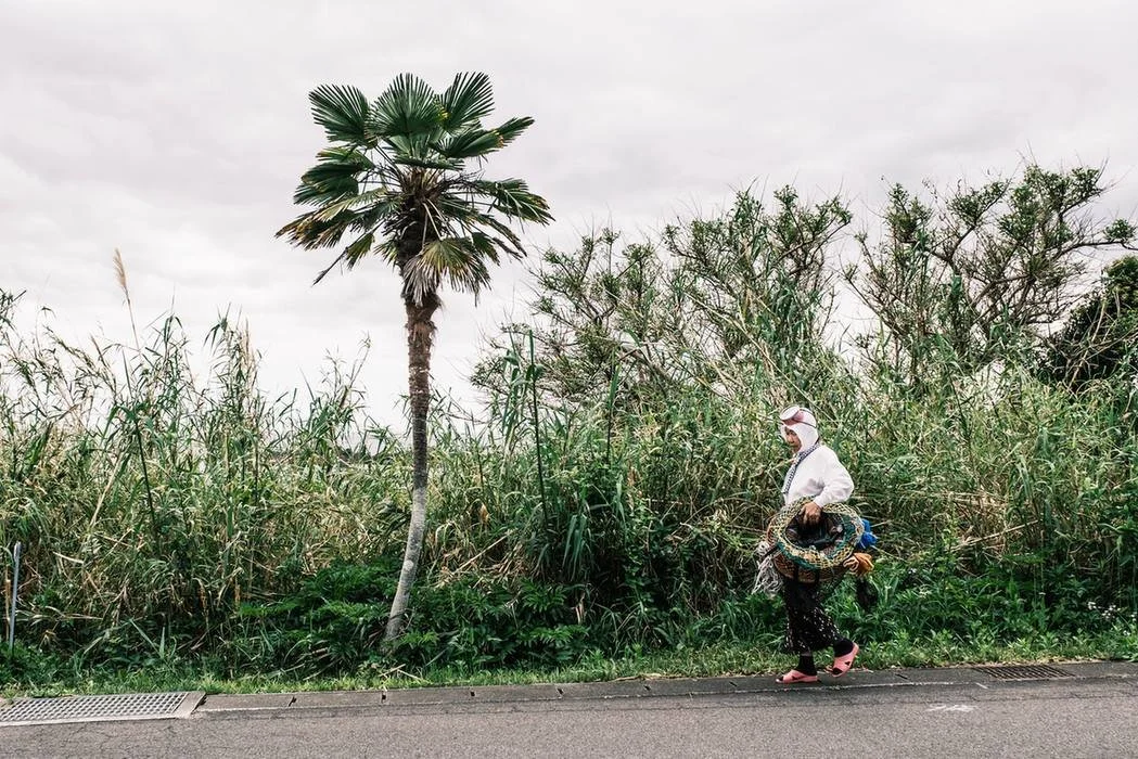 Ama diver walking with diving equipment by side of road in Iseshima, Mie prefecture, Japan.