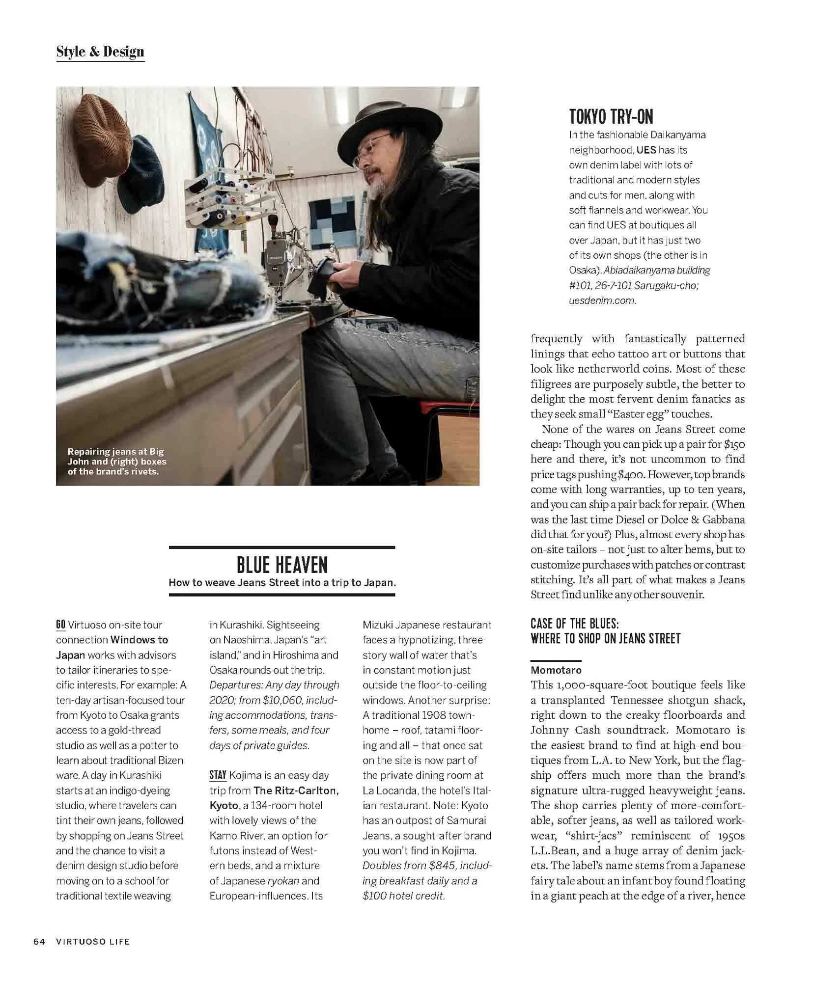 A man with long hair and beard, wearing a black hat and glasses, sewing jeans at a workbench in a denim repair shop, with hats hanging on the wall and fabric stored above.