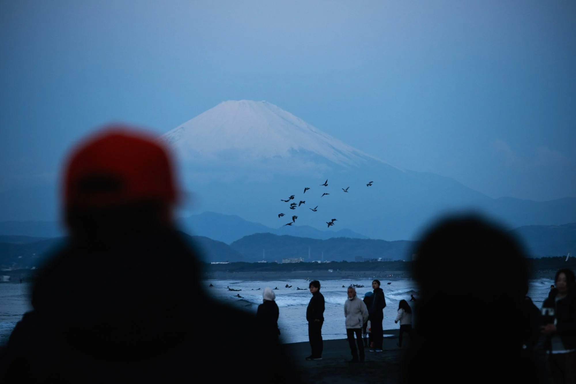 People stand on a beach waiting for the first sunrise of the new year in Fujisawa, Japan, with Mt. Fuji in the background.