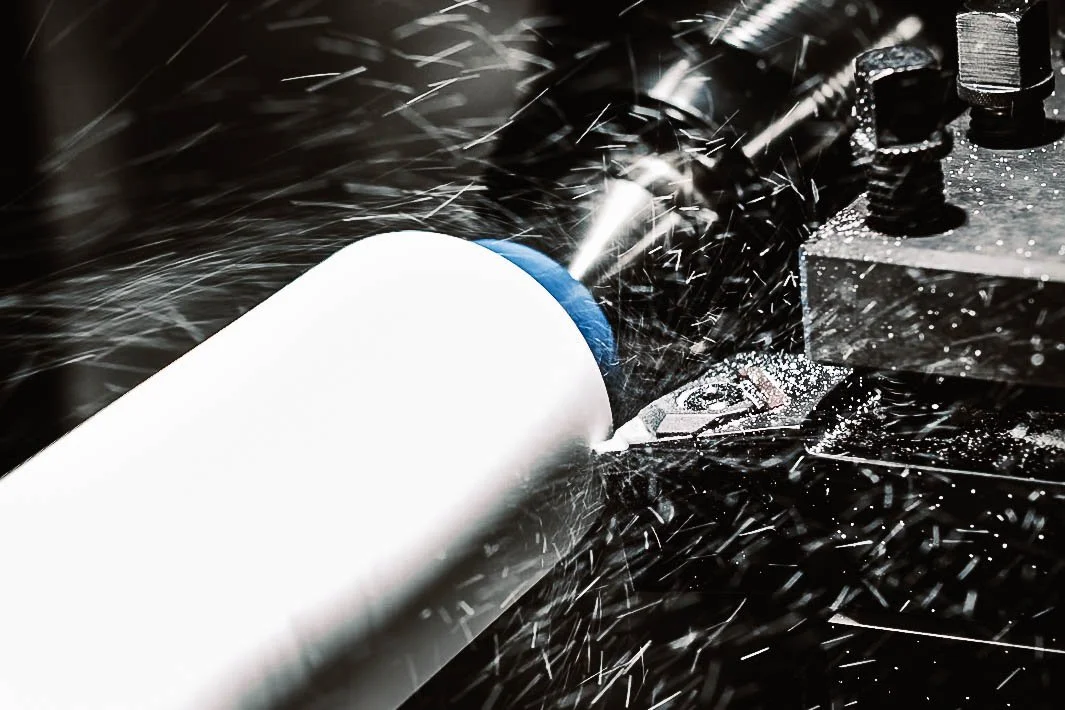 An industrial cutting machine shapes a cylindrical component on a lathe.