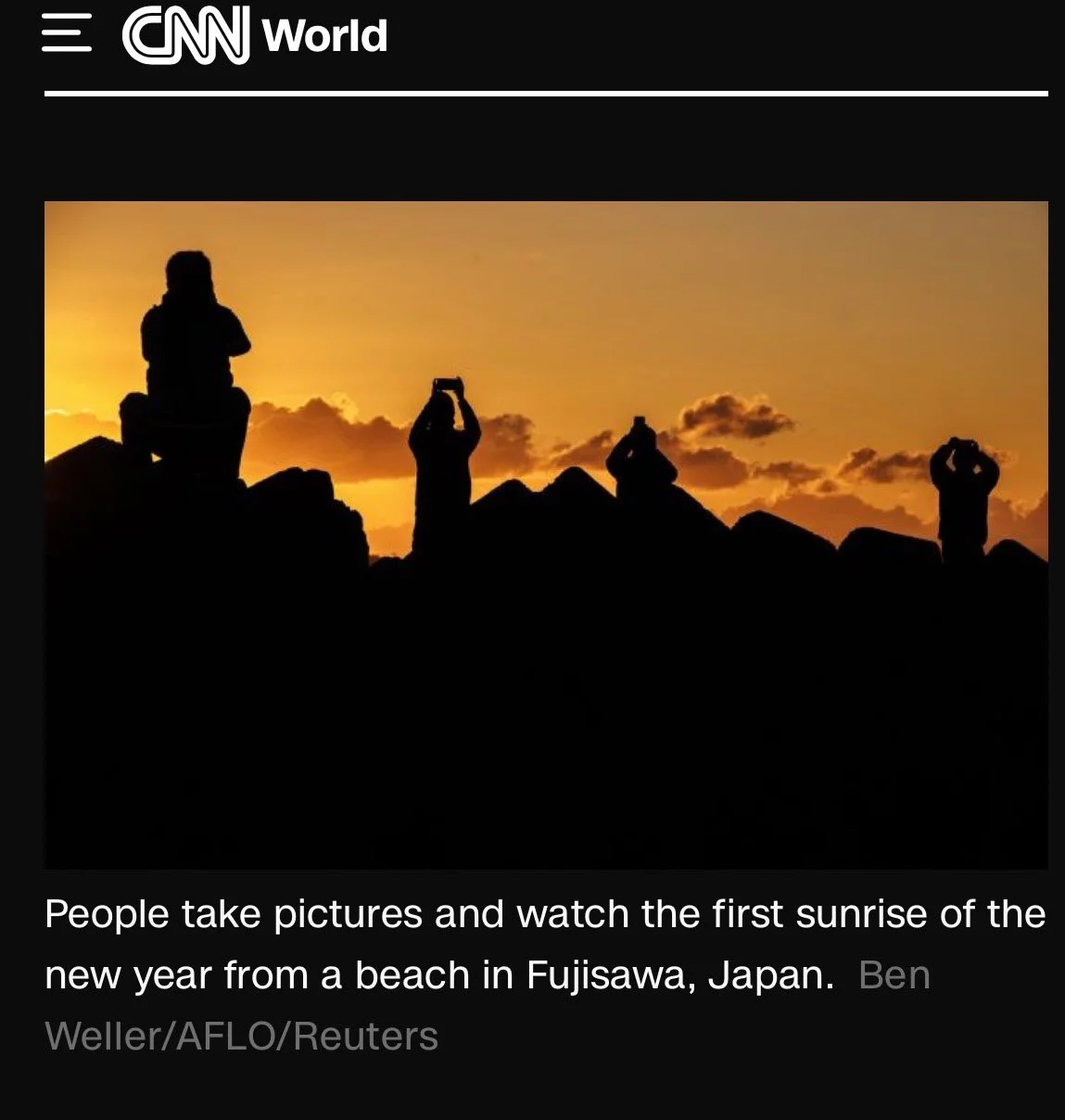 People take pictures of the sunrise at a beach in Kamakura, Japan.