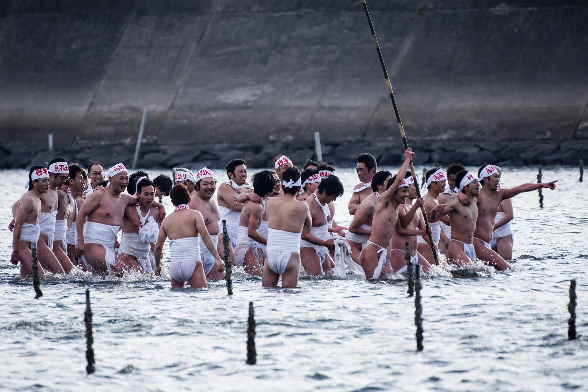 Group of men dressed in traditional Japanese loin cloths, wading in water, participating in a festival