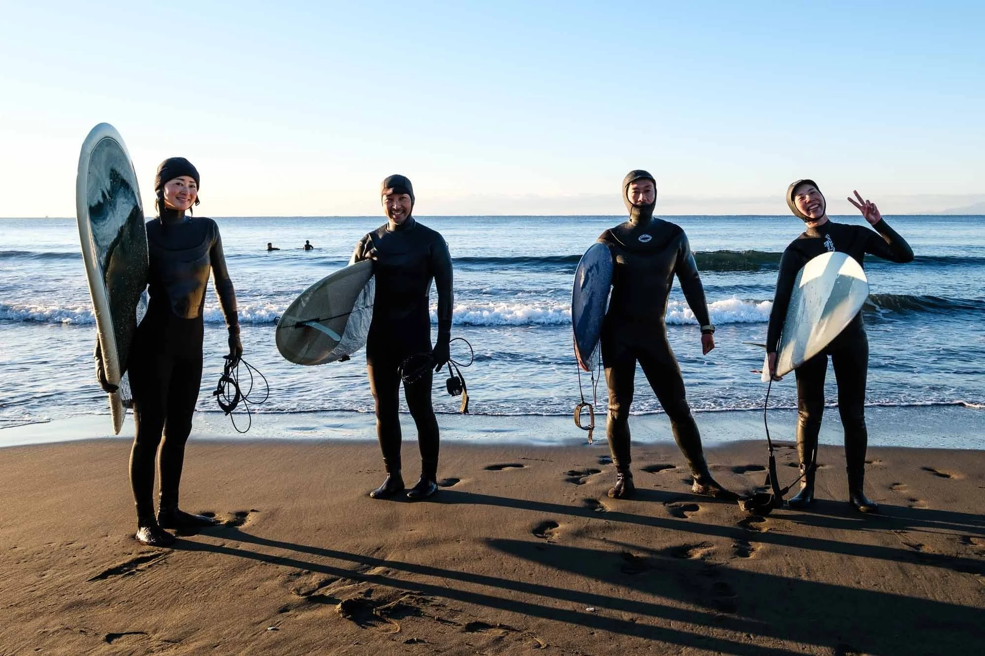A group of surfers wearing wetsuits pose for a candid portrait at Kugenuma Beach in Fujiswawa on New Year's Day, 2025.