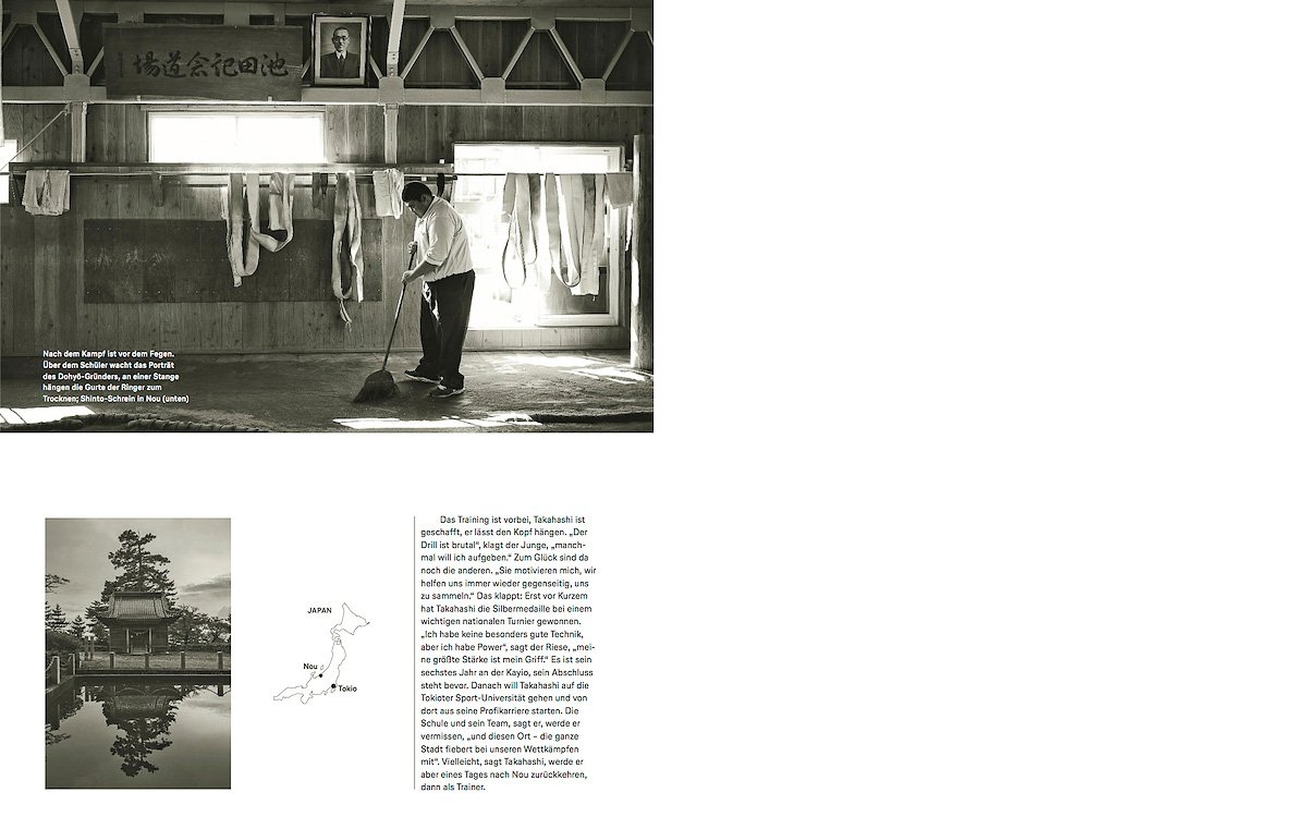 Black and white interior of a wooden training hall with a man sweeping the floor of a sumo dojo.