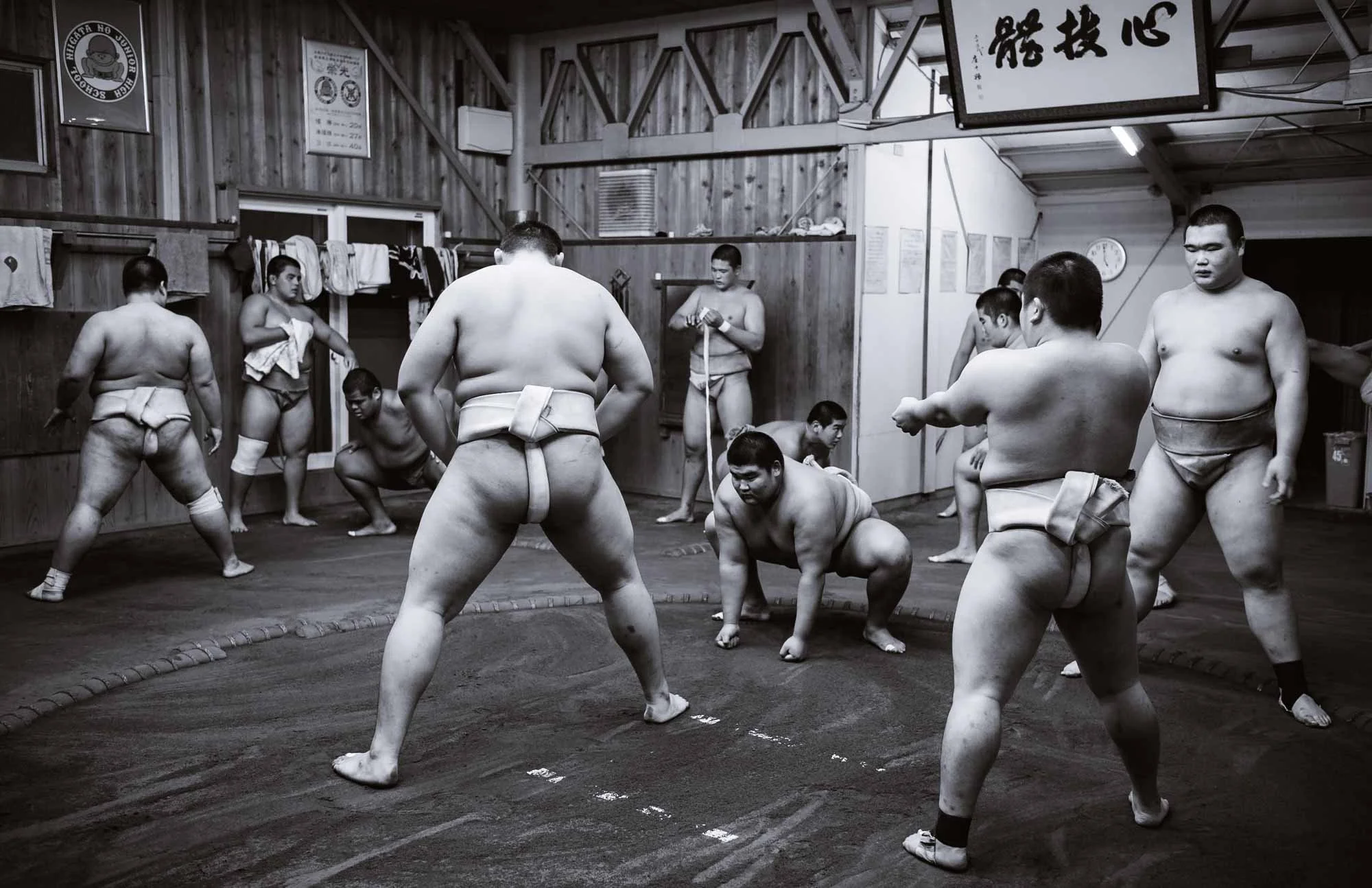 A black and white image of young sumo wrestlers practicing in a dojo.