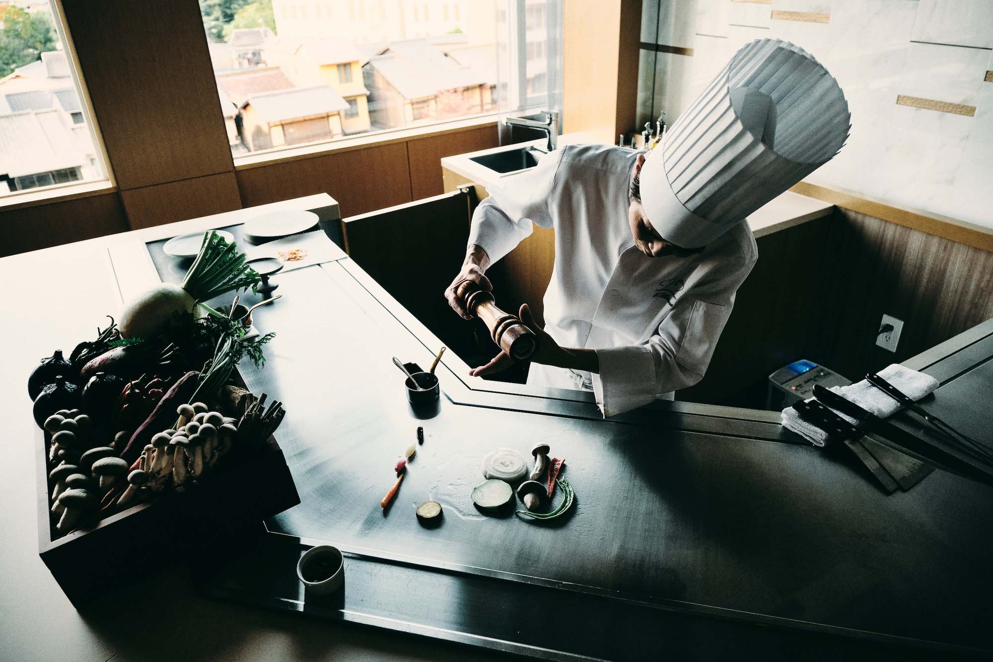 Chef grilling vegetables on large iron grill at luxury hotel restaurant, photographed by Ben Weller, a photographer specializing in hospitality photography in Japan.