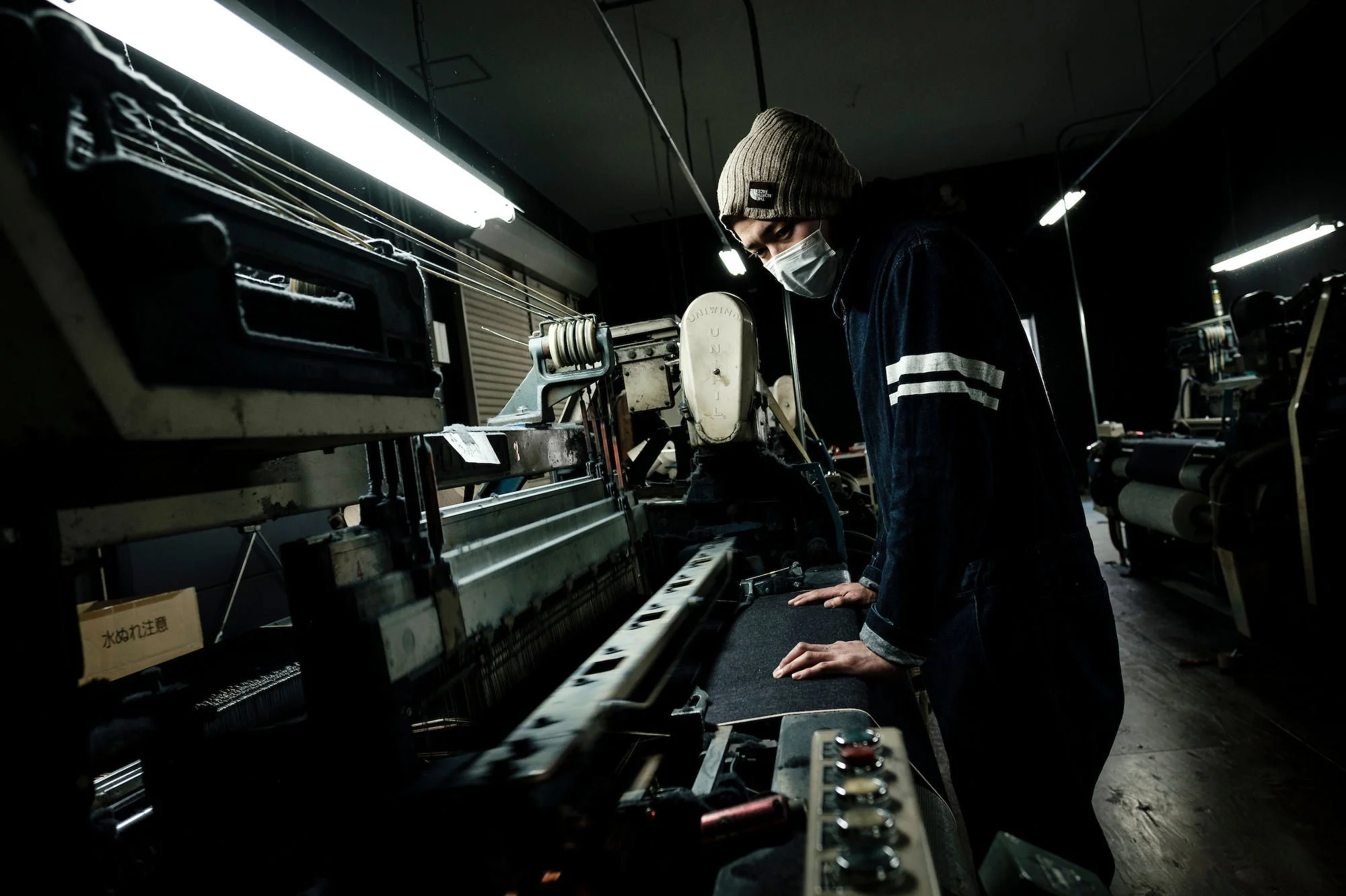 Workshop employee operating a denim weaving loom.