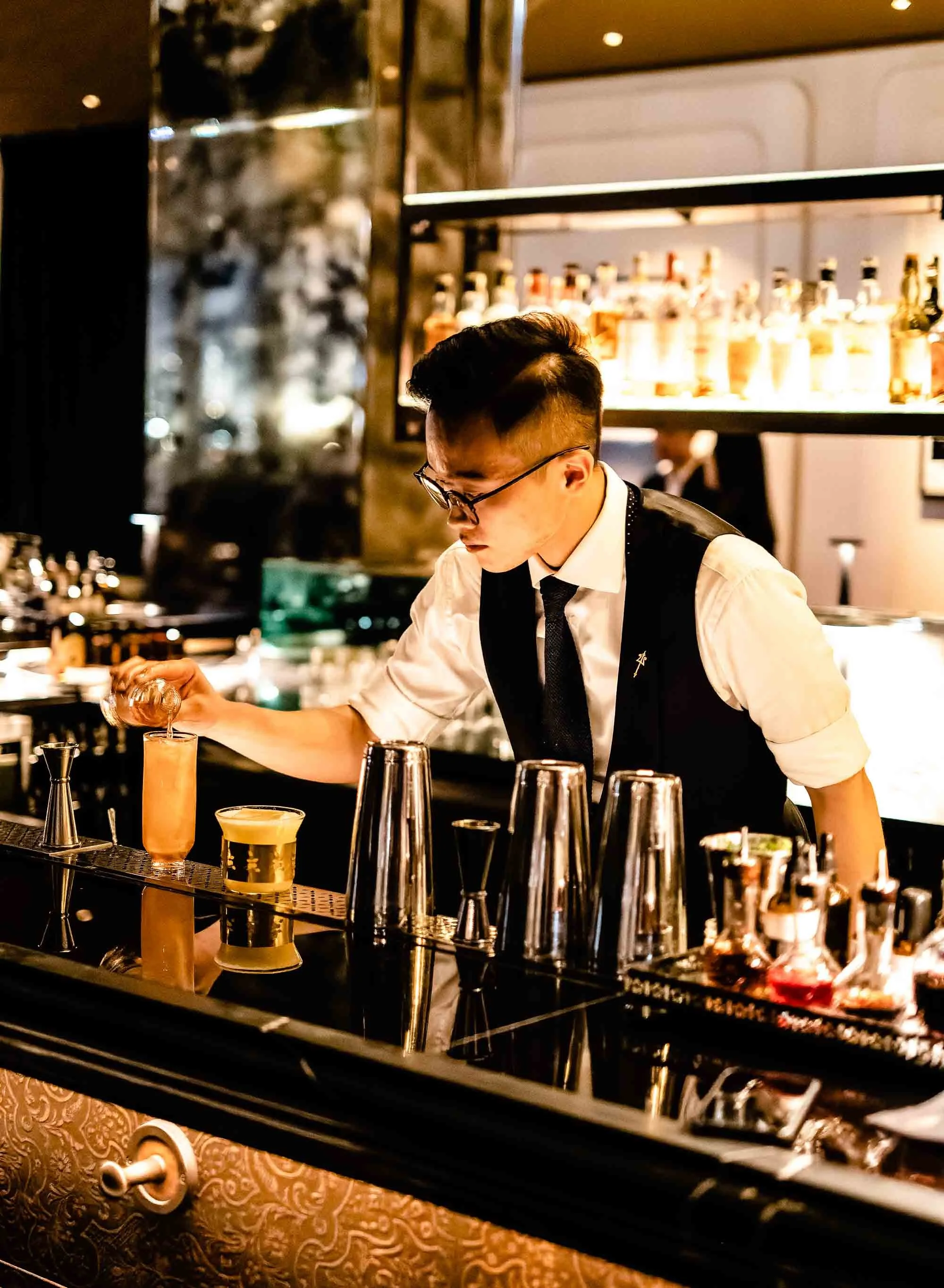Bartender preparing cocktails with precision at upscale Hong Kong hotel bar.