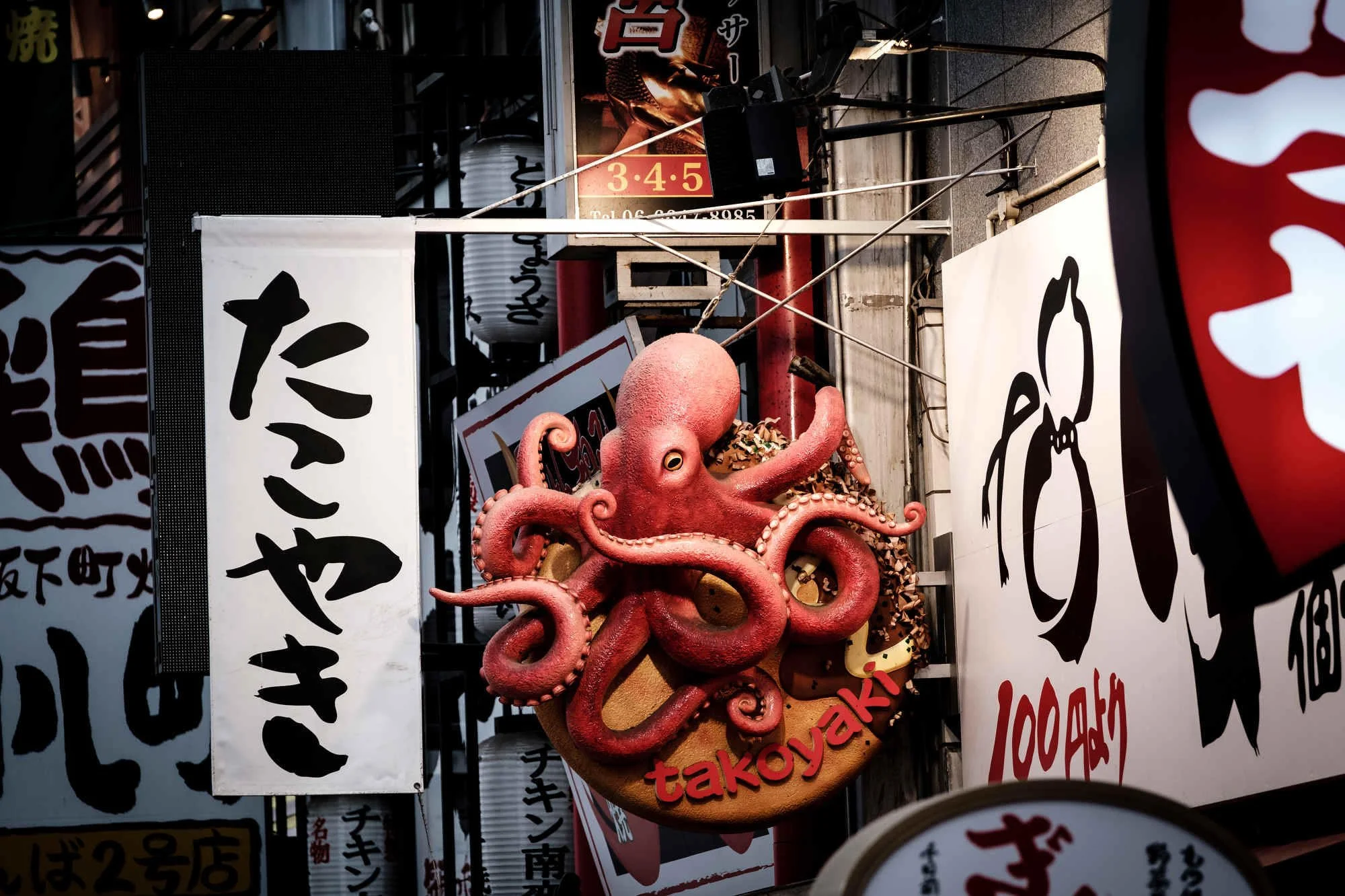 Colorful sign of an octopus with the text 'takoyaki' in front of a restaurant in Osaka.