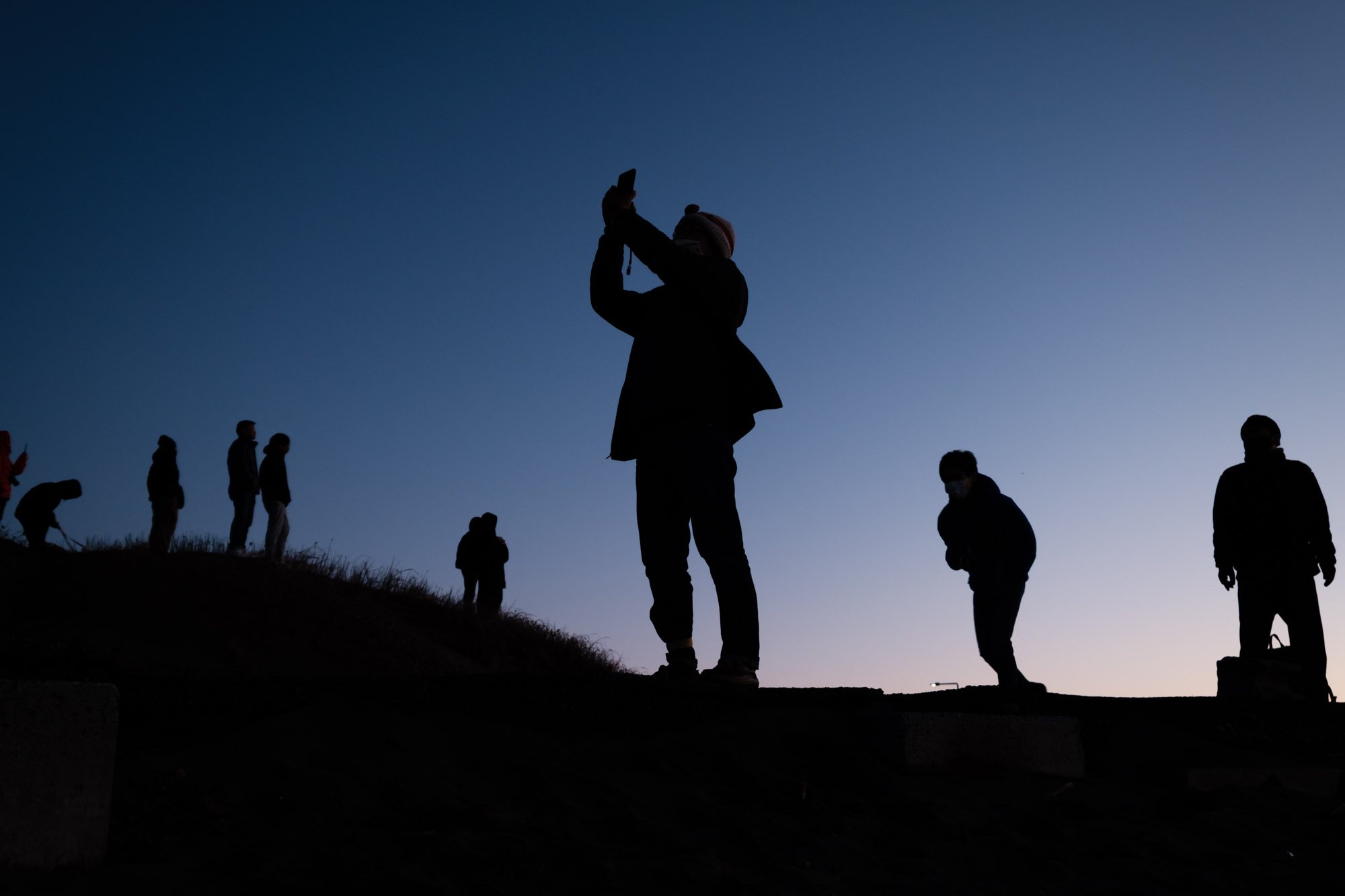 Silhouettes of people watching the first sunrise of the new year at a beach in Fujisawa, Japan. By Japan travel photographer Ben Weller.