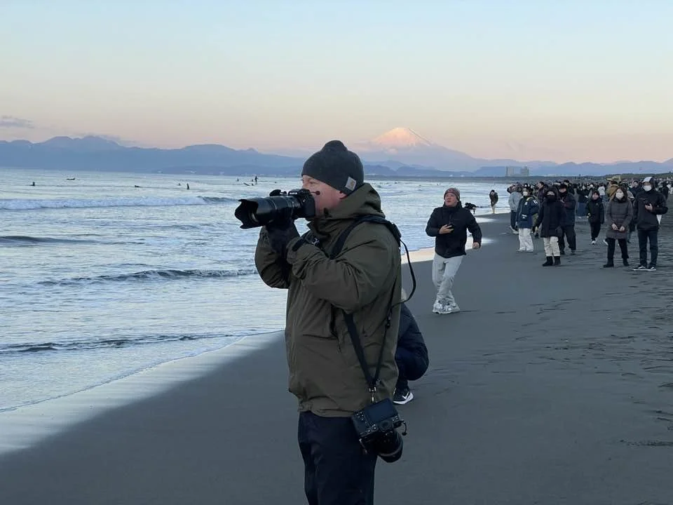 Japan travel photographer Ben Weller photographing Japanese cultural tradition hatsuhinode on a beach with Mt. Fuji in the background.