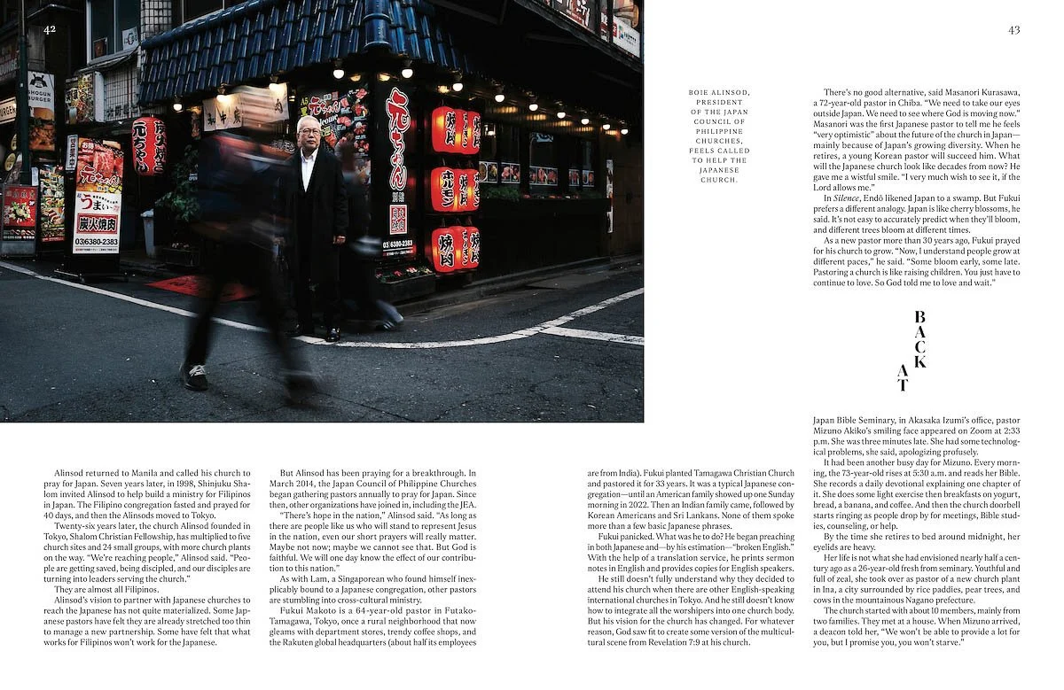 Night scene of a man in a black coat walking past a Japanese restaurant with red lanterns and signage, with blurred pedestrians on a city street.