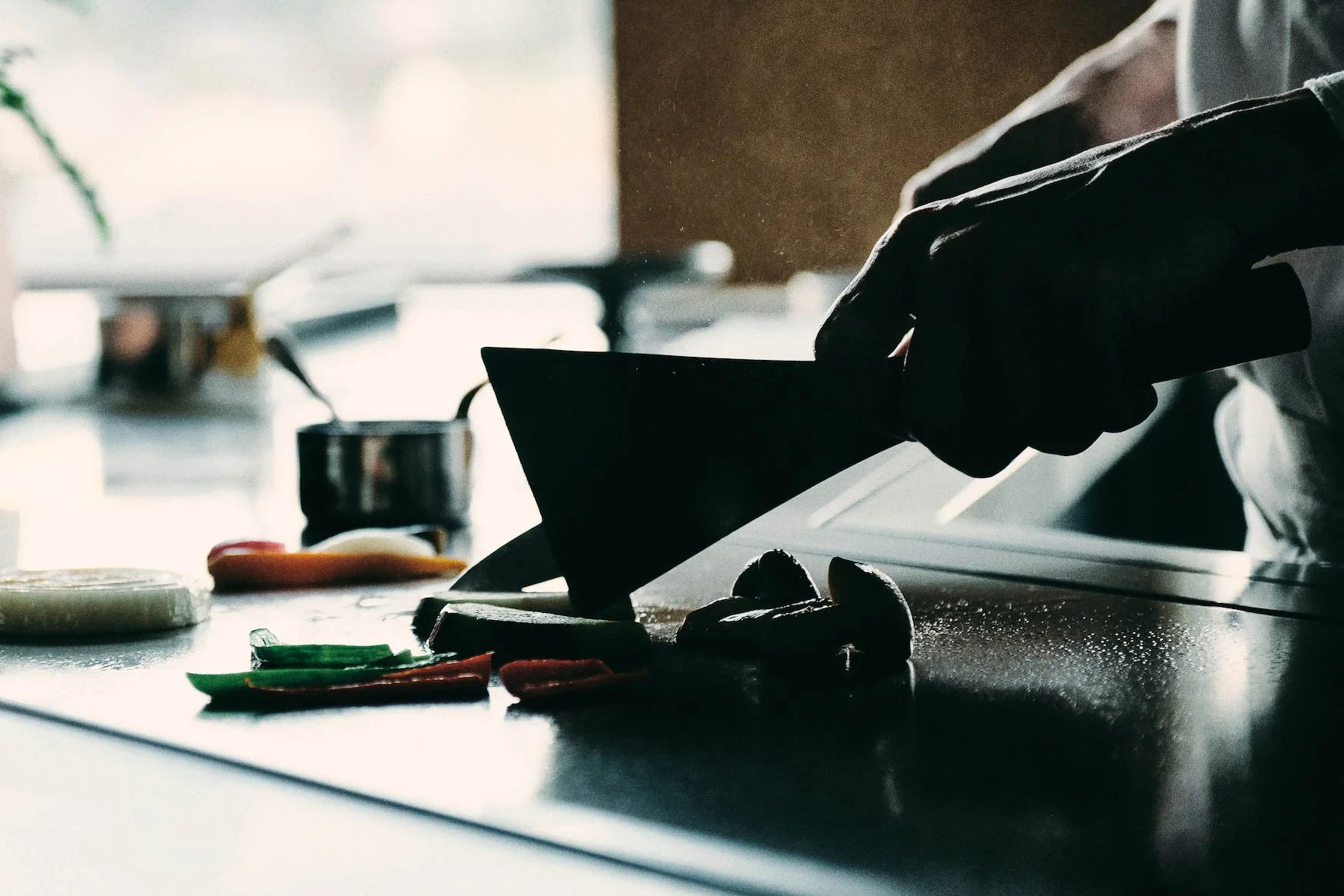 A chef grills vegetables on a teppanyaki grill, with various vegetables and kitchen items nearby.