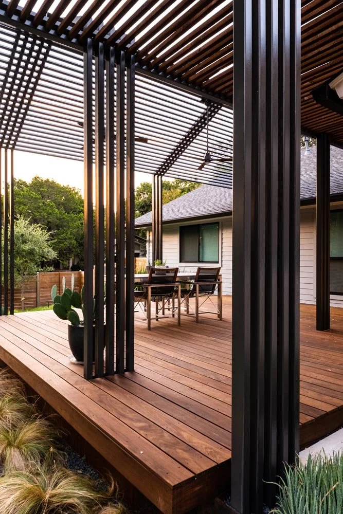 Steel planter and vertical steel pergola detail anchoring a raised hardwood deck at sunset