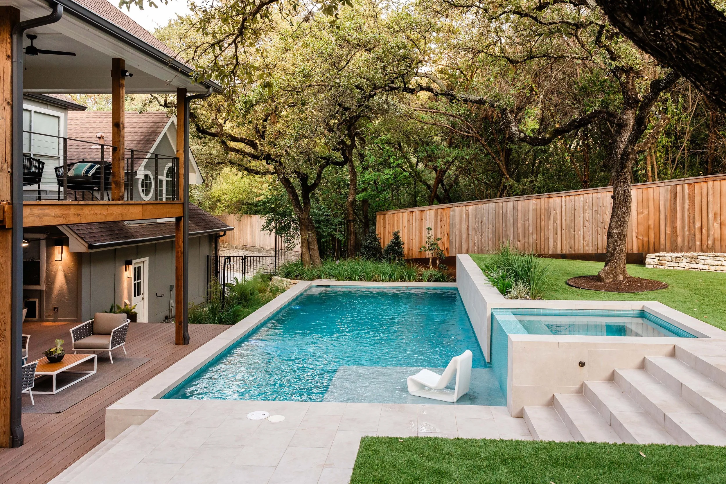 Linear lap pool with spa, surrounded by large format porcelain tile decking and horizontal cedar privacy fencing