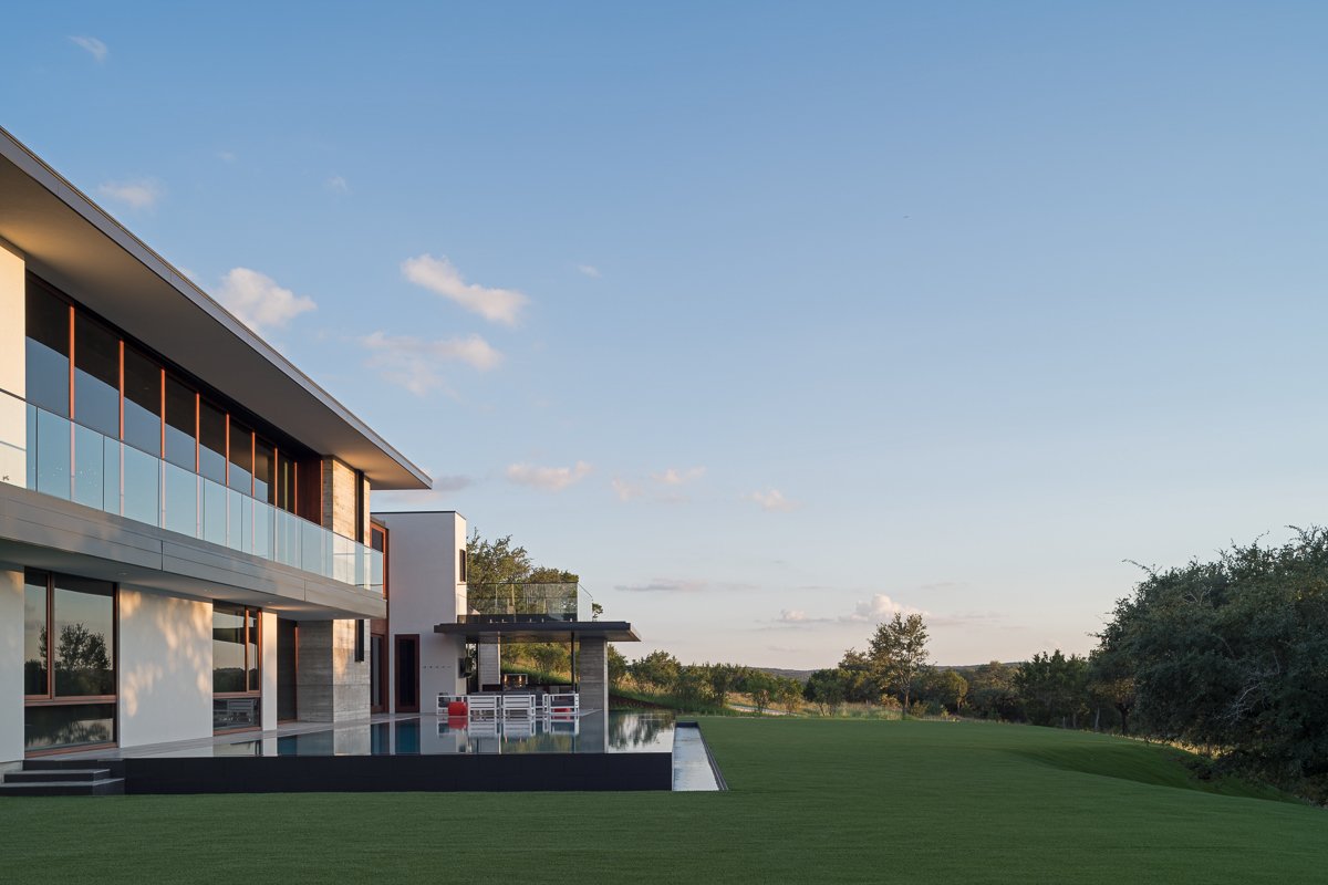 Modern hillside residence with sweeping lawn and elevated infinity-edge pool overlooking Hill Country horizon
