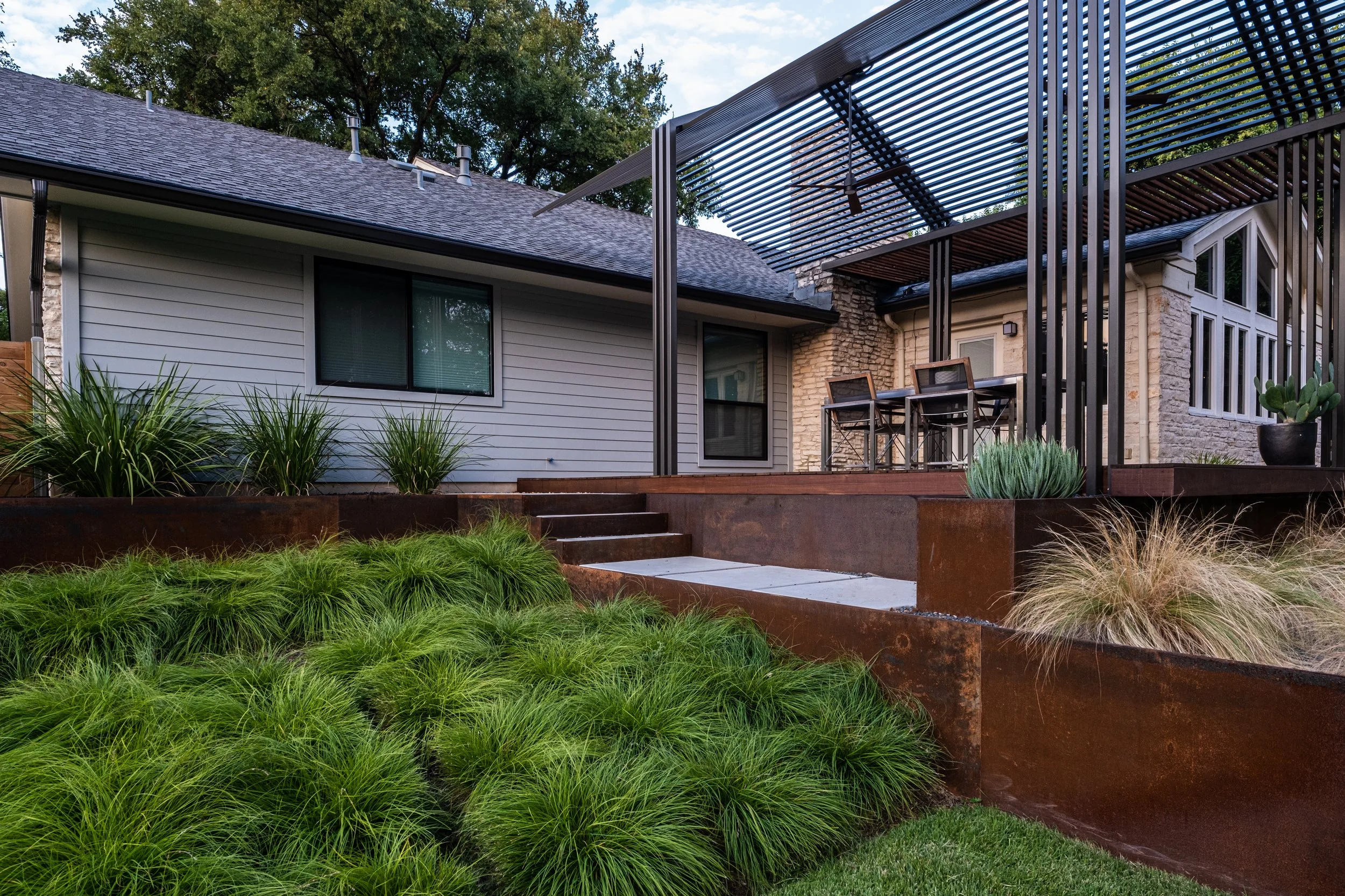 Steel terracing with integrated landscape stairs and modern pergola over a raised patio