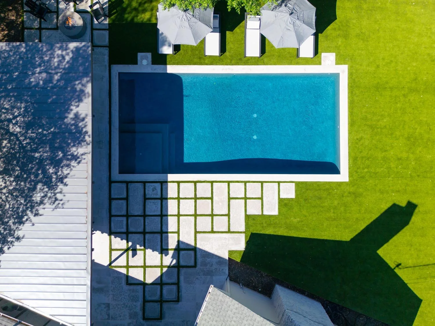 Top-down image of minimalist pool design with structured layout and contrasting textures of turf and stone.