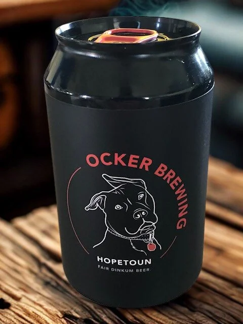Black can with the Ocker Brewing and Hopetoun logos, featuring a dog head outline, sitting on a wooden surface.