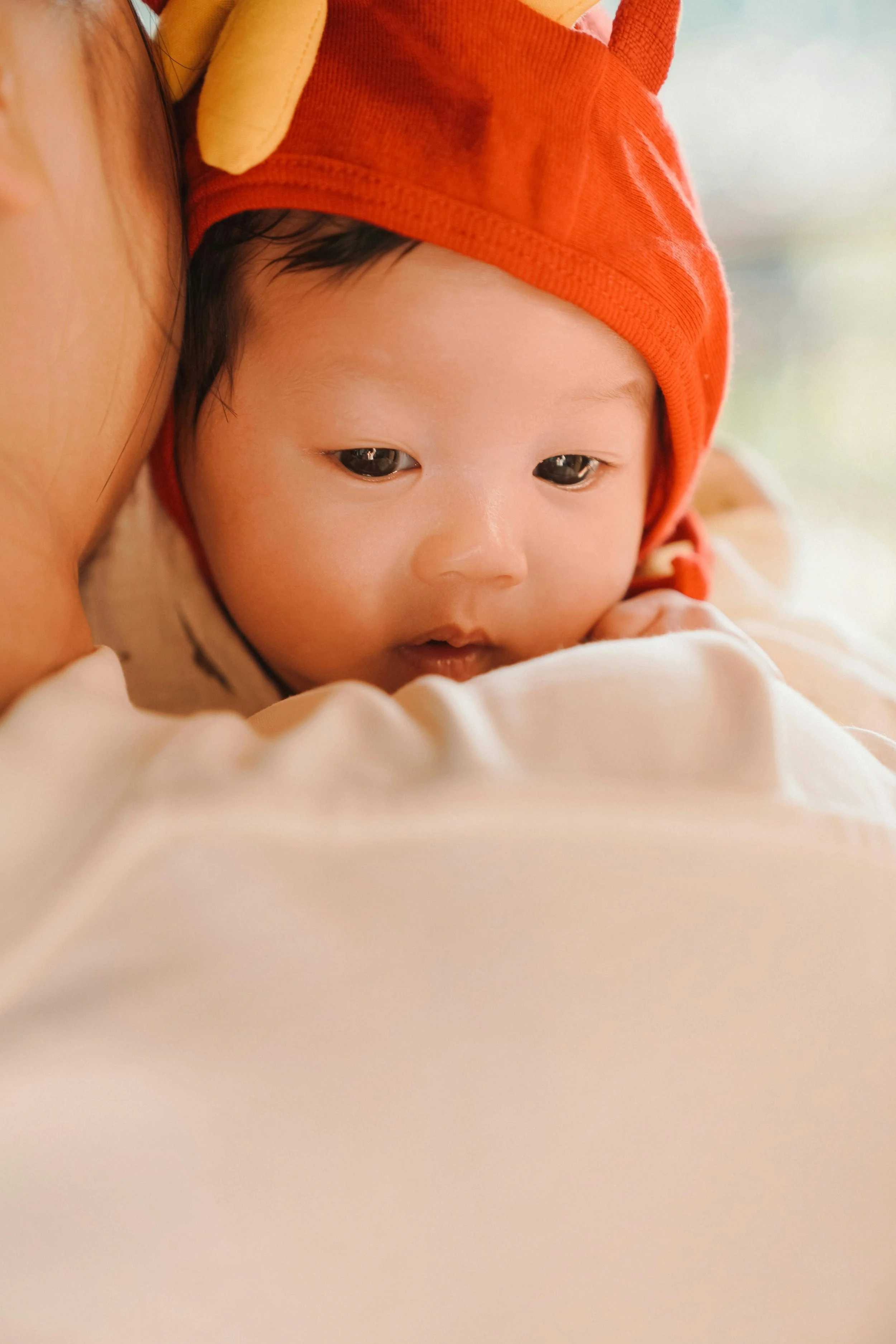 A woman smiling and holding a baby on a gray couch in a living room.