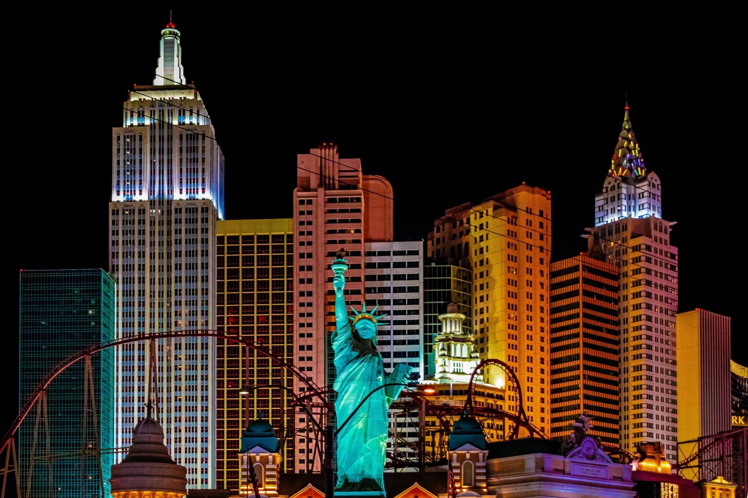 Silhouette de la Statue de la Liberté illuminée de nuit, avec un panorama de gratte-ciel lumineux de Las Vegas en arrière-plan.