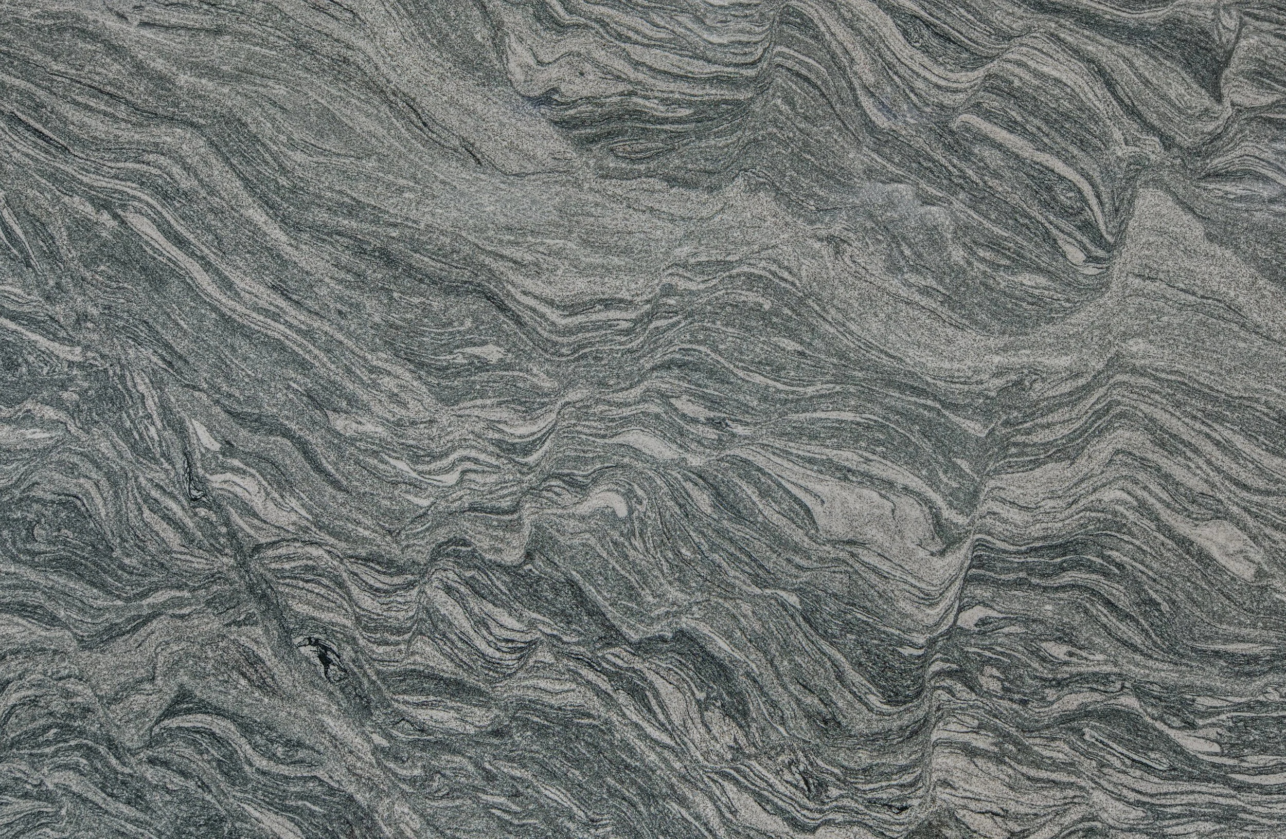Close-up view of layered, wavy gray and white marble stone pattern.