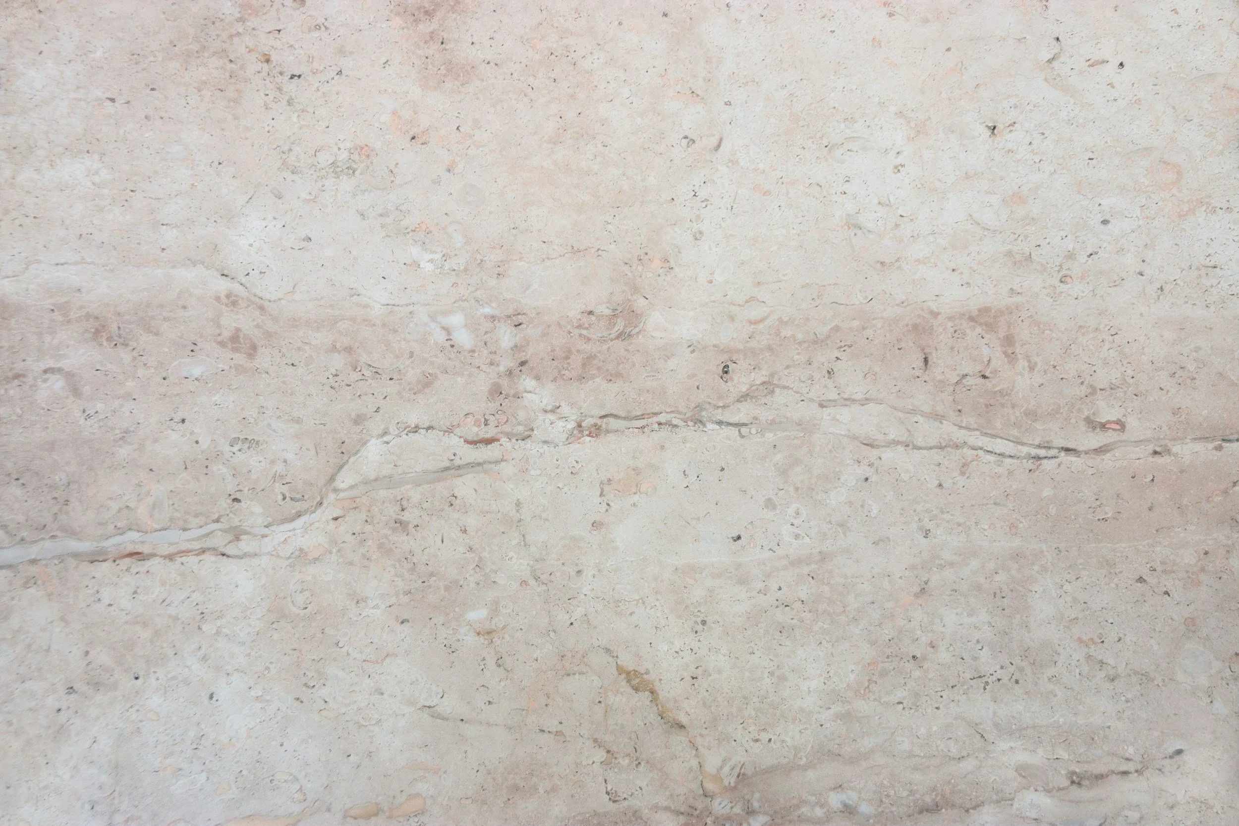 Close-up of a light beige marble surface with natural veining.