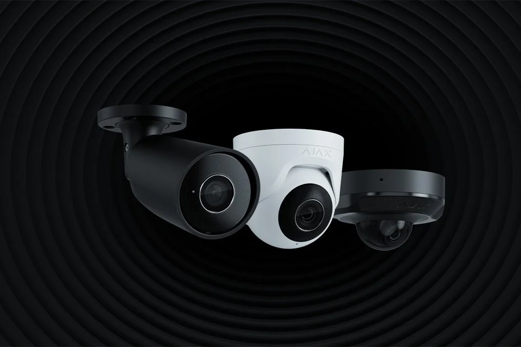 Three security cameras, two black and one white, against a black circular textured background.
