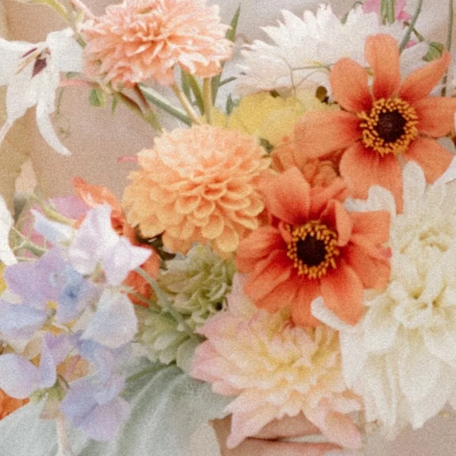Image of a close up of a floral bouquet with beautiful pastel yellow, orange, purple, pink, and white flowers.