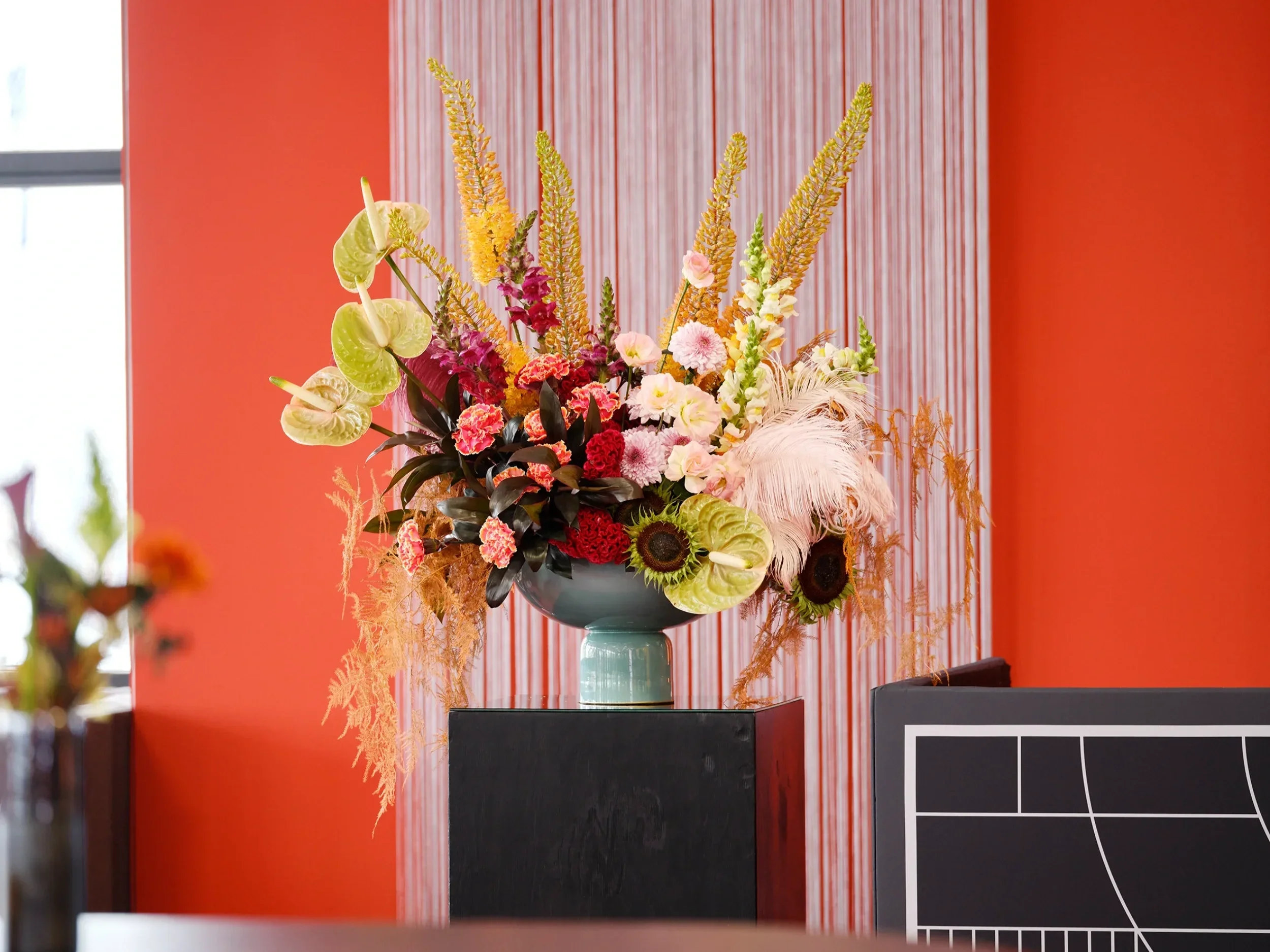 Event floral installation with anthurium, carnations and feathers on black pedestal at Formula E Berlin 2025 Tempelhofer Feld