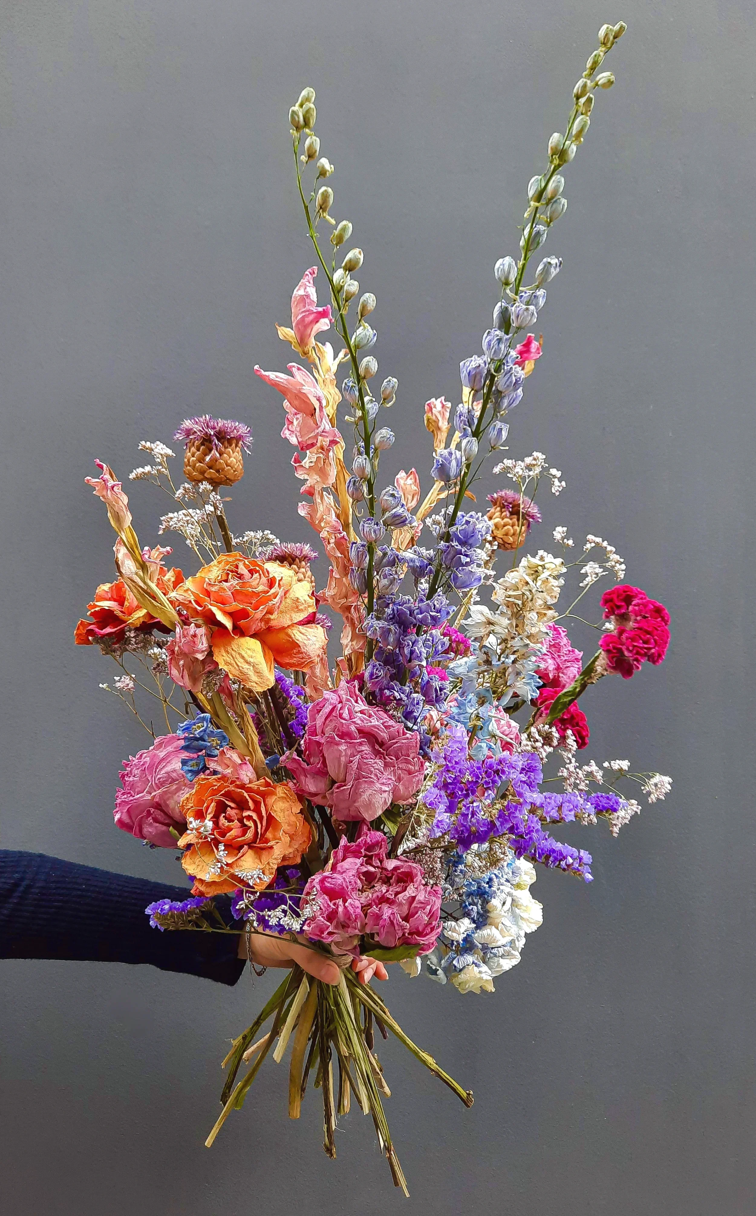 Dried flower arrangement with roses, delphinium and statice held by hand, Berlin 2023