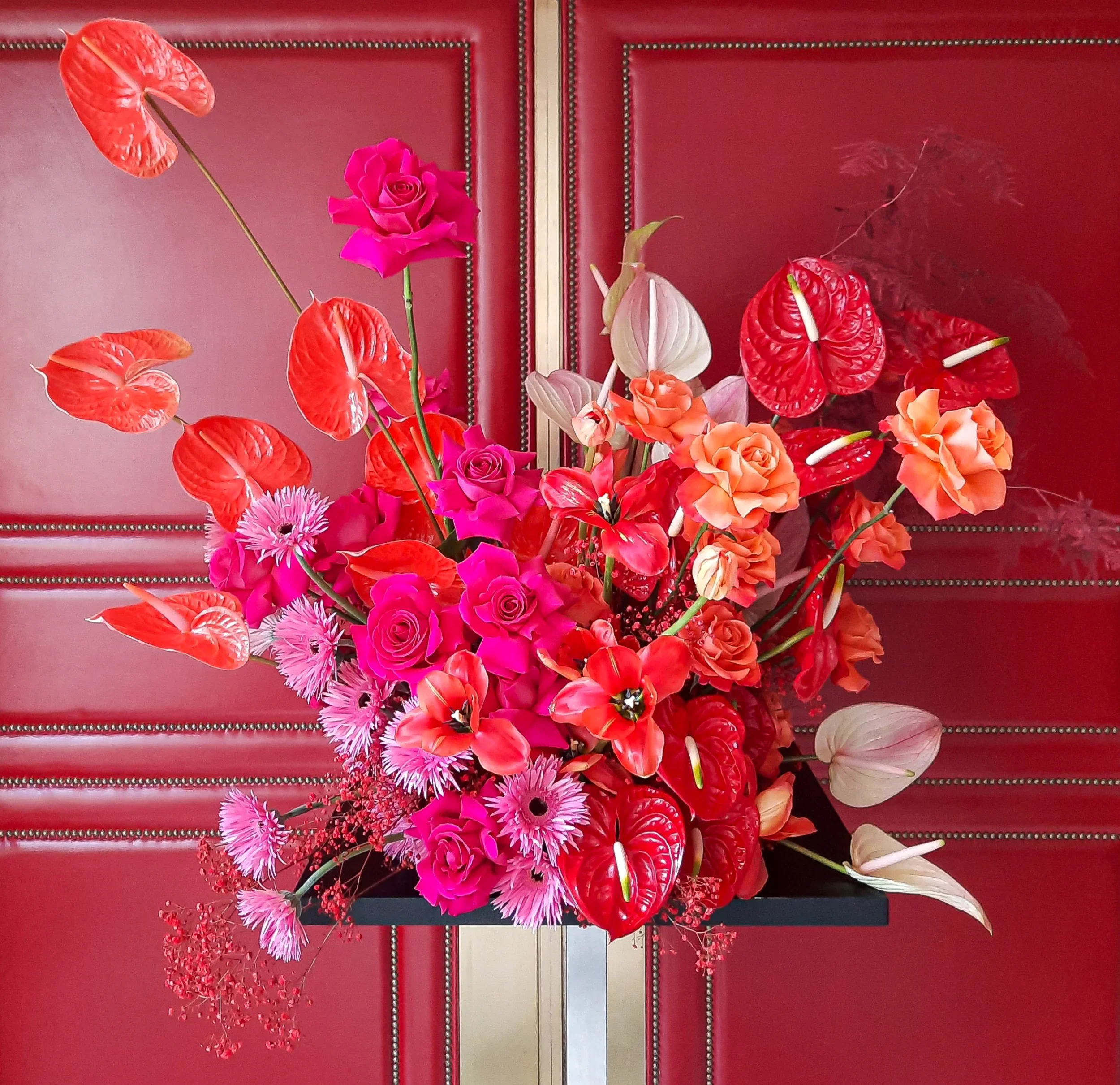 Floral design with anthurium and roses against red door at Hotel Adlon Berlin, Bundespresseball 2023