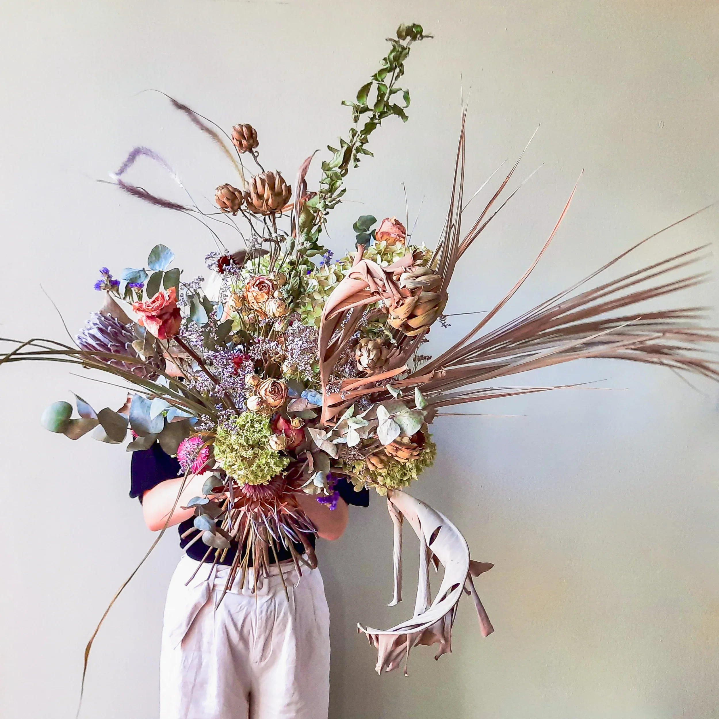 Dried floral arrangement with peonies, gladiola and statice against neutral background