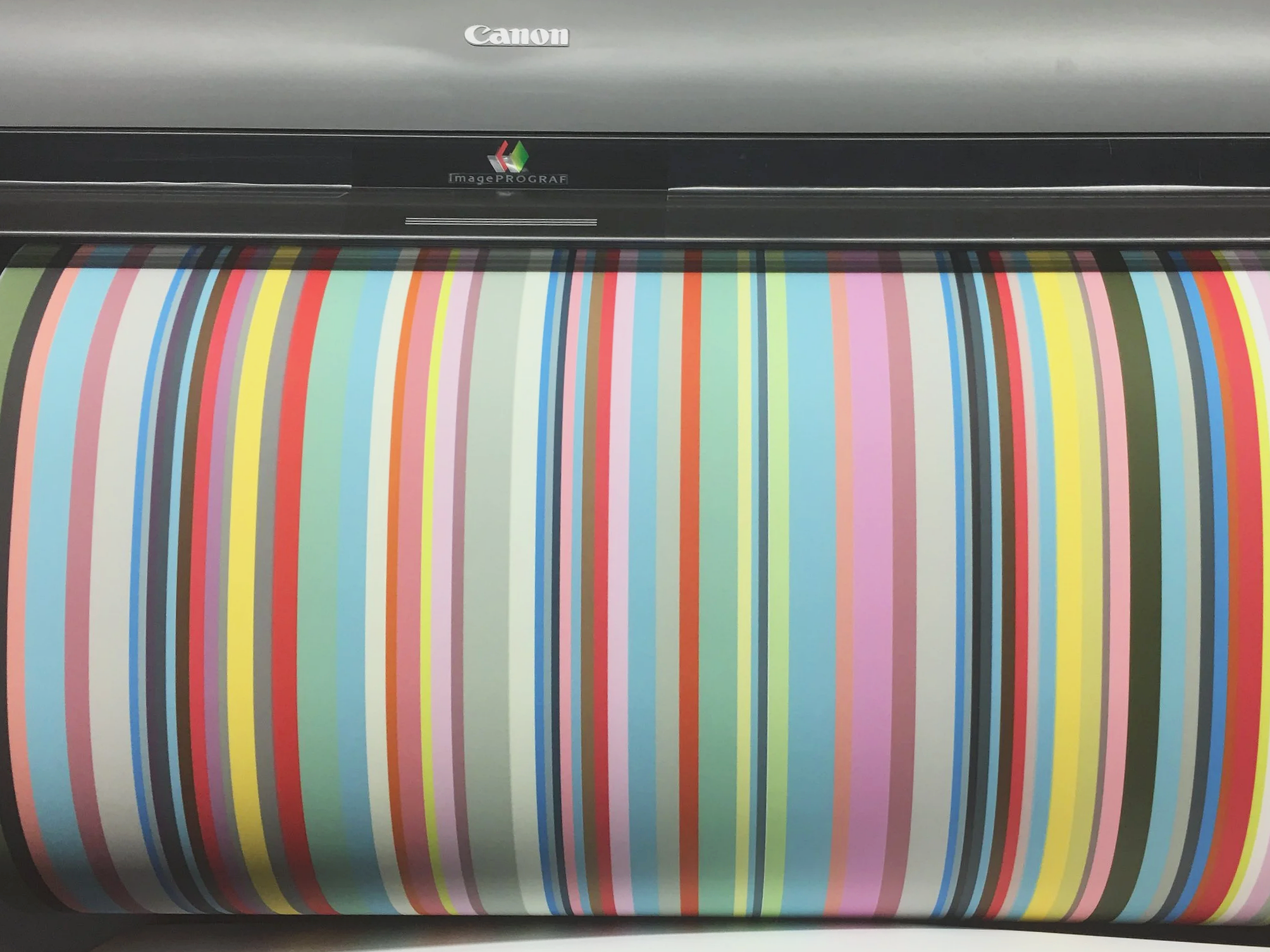 A large printer is printing a multicolored test pattern with vertical stripes of various colors.
