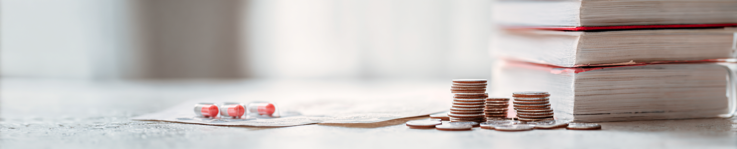 Stack Bücher, Münzen, Medikamente auf einem Tisch.