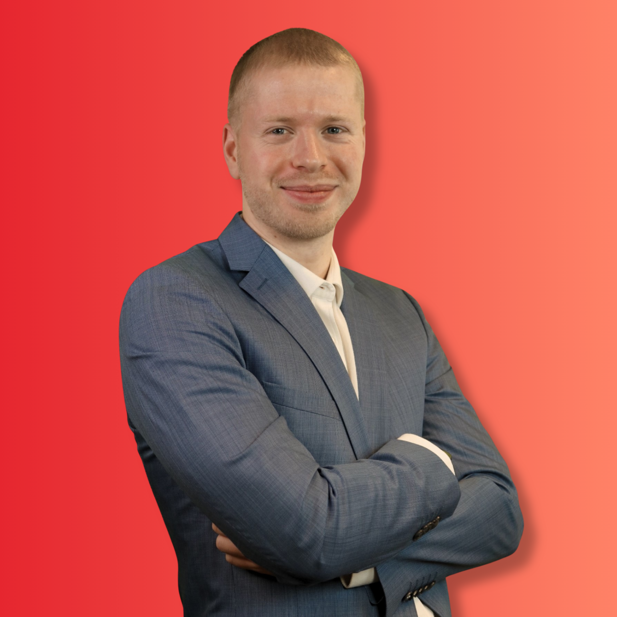 Ein Mann in einem blauen Anzug mit weißen Hemd steht vor einem rot-orangenen Hintergrund und lächelt.