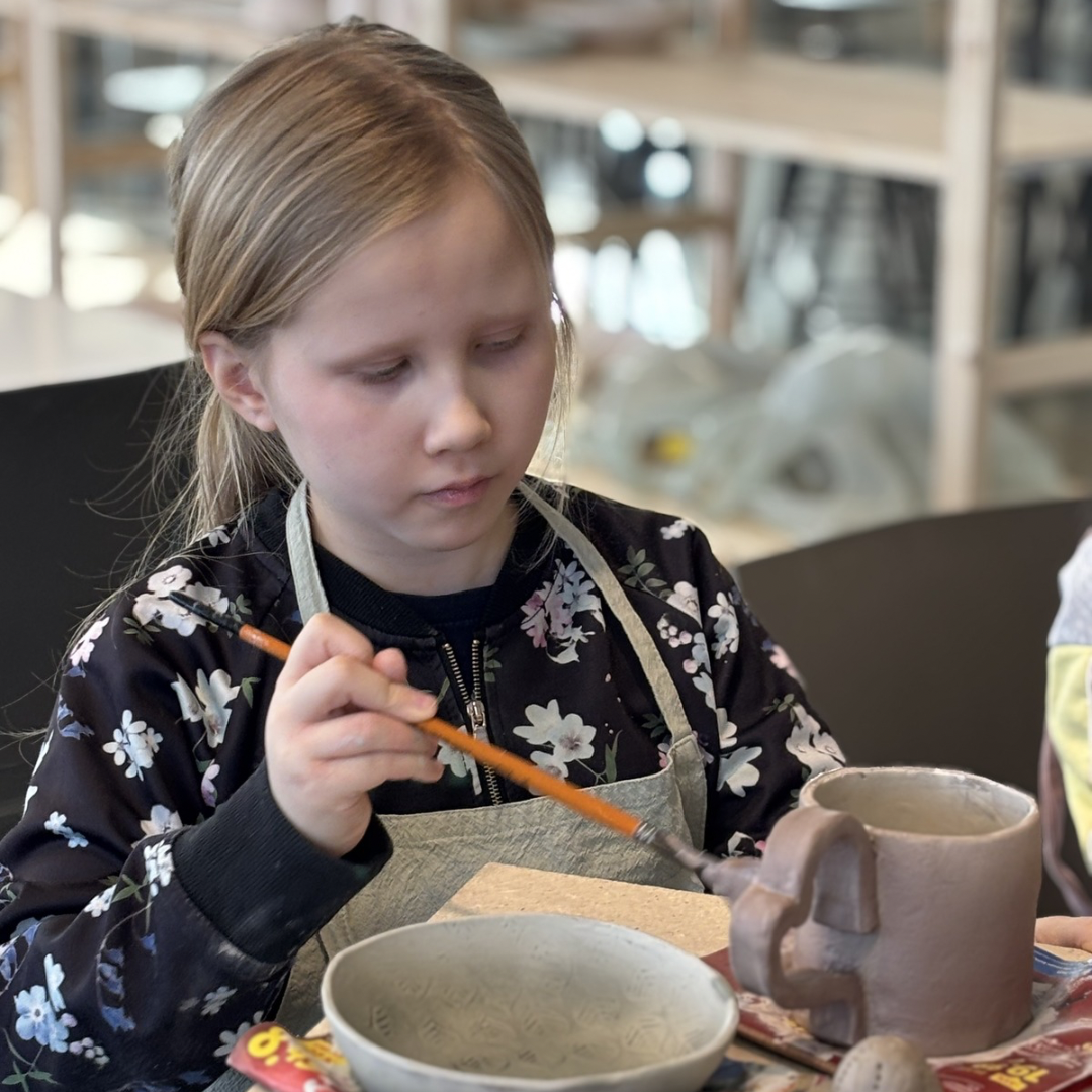 lapsi maalaa keramiikkastudiolla tekemäänsä kurpitsaa