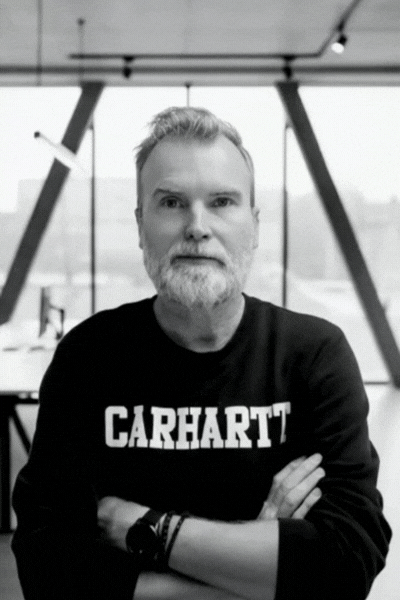 Black and white photo of a middle-aged man with a beard, short styled hair, looking to the side, wearing a dark button-up shirt.