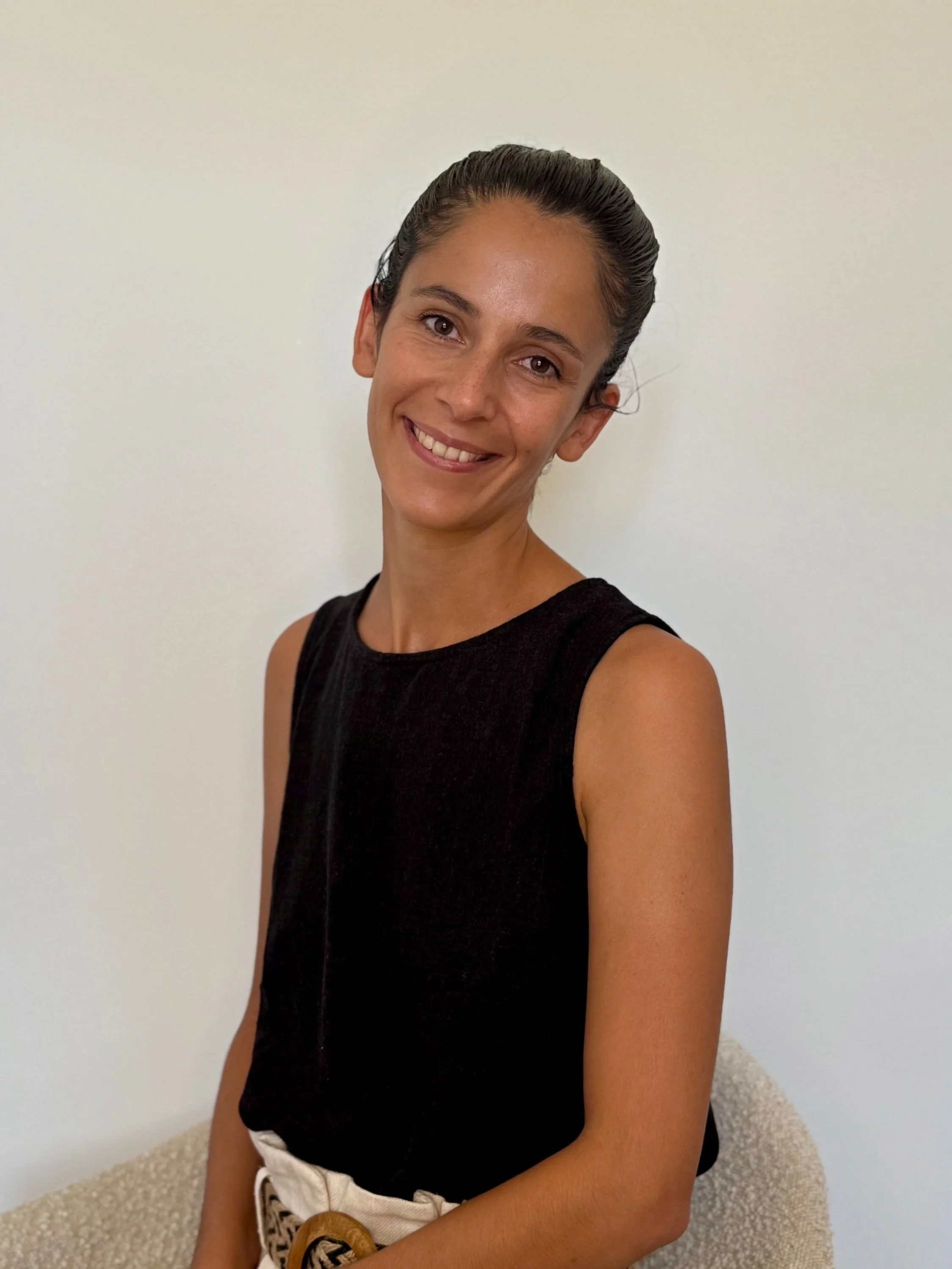 Portrait de Julie, la fondatrice de Moya Sync - Logiciel de gestion conciergerie location saisonnière, une femme souriante portant un haut noir et un pantalon beige