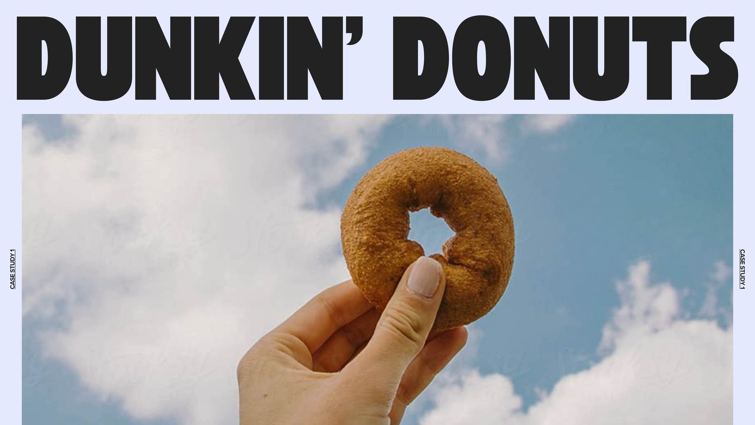 A hand holding a fried donut ring against a partly cloudy blue sky with the words 'DUNKIN' DONUTS' in large black letters at the top.