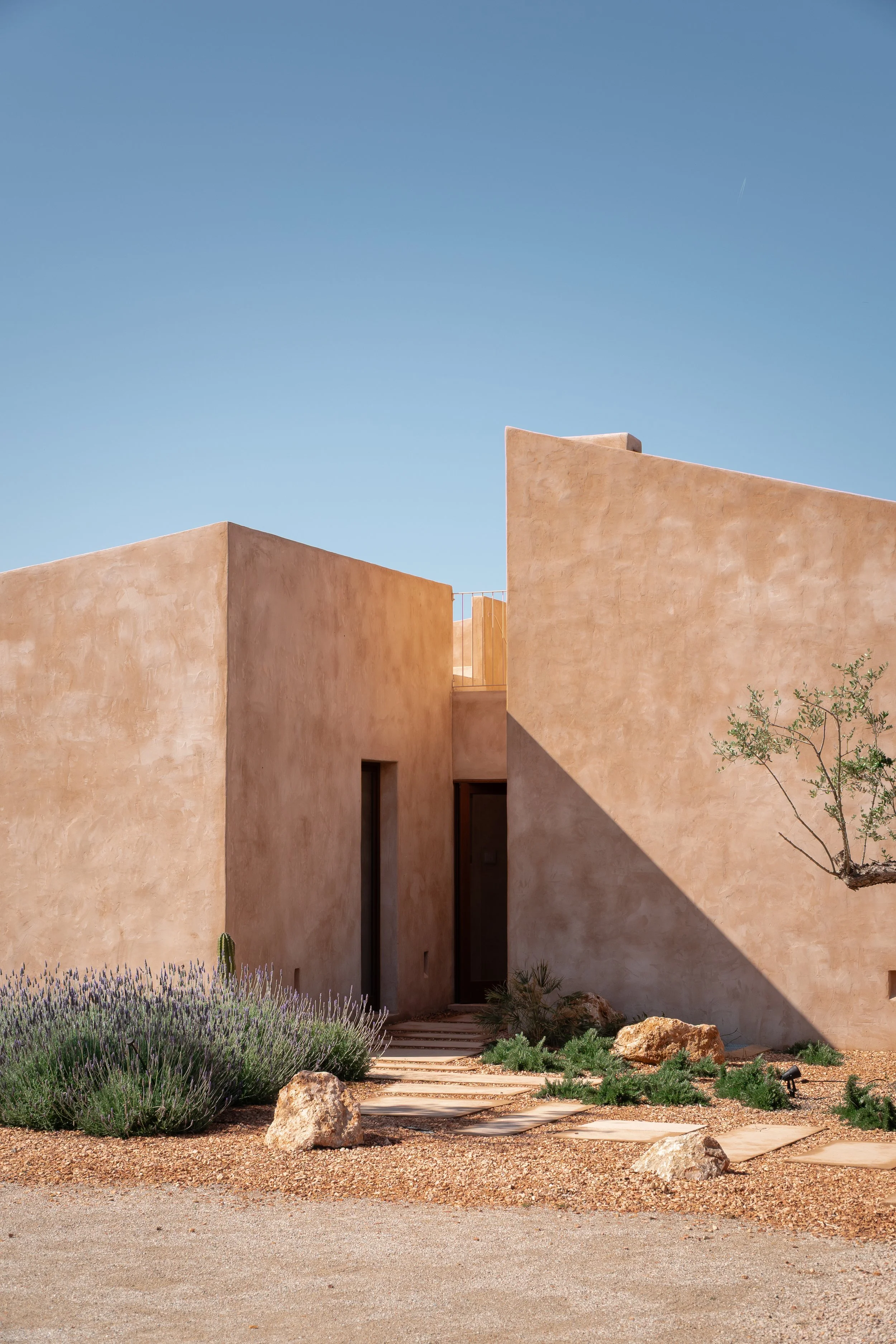Outdoor terrace with dry-stone walls and native planting, contemporary Mallorcan finca by Munarq