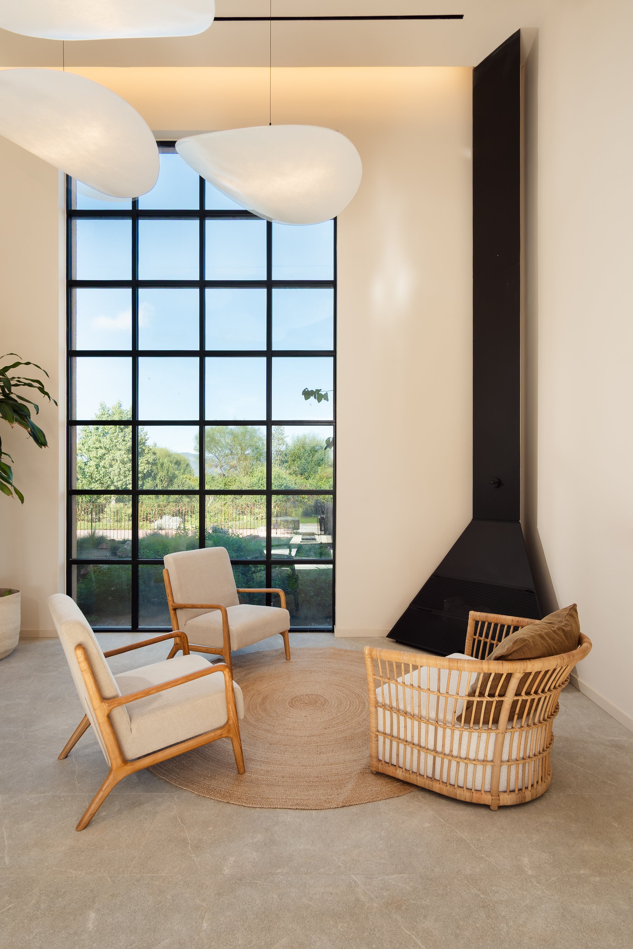 Minimalist interior with rattan chair and steel-frame windows, contemporary finca Mallorca