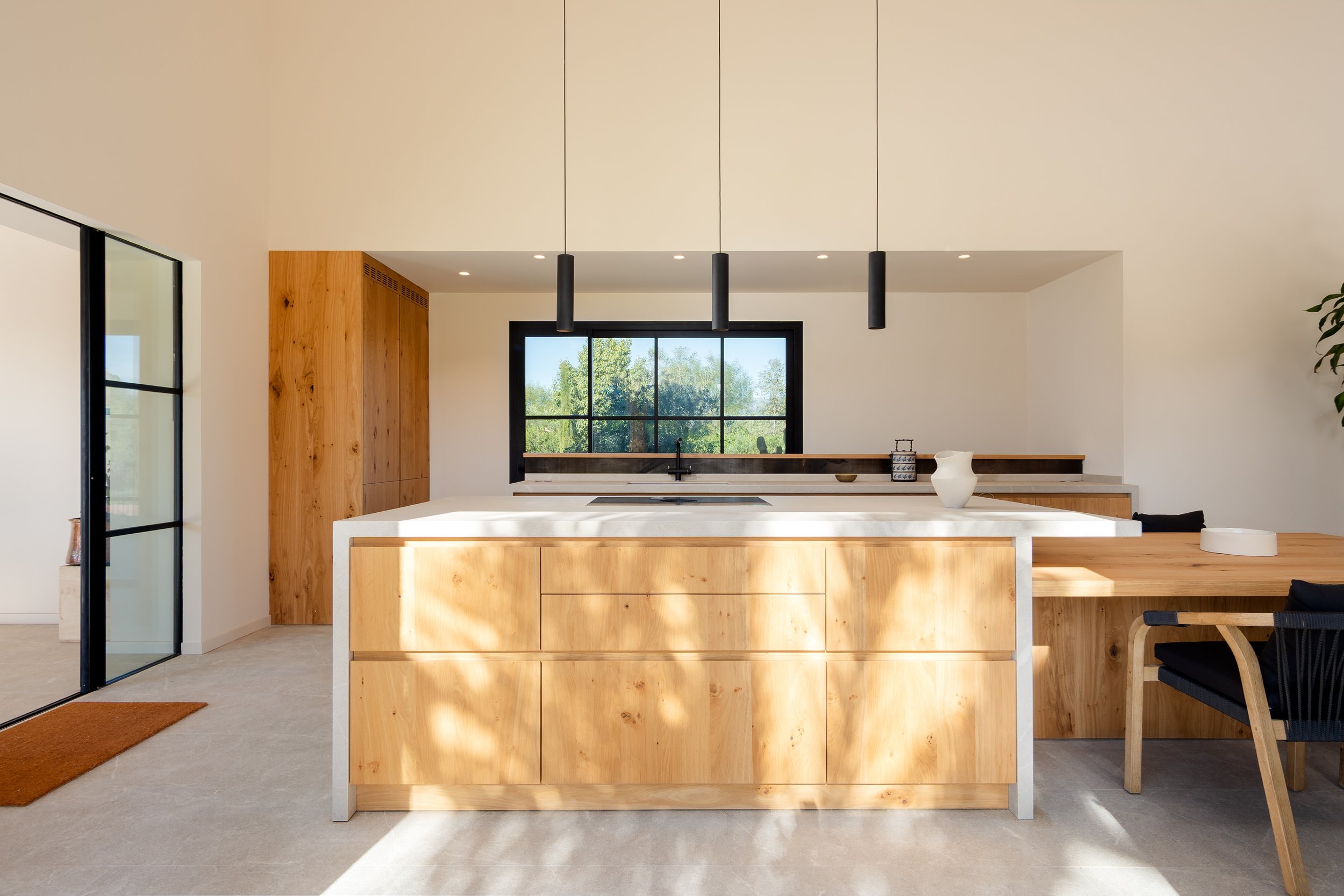 Open-plan kitchen with raw oak island and black pendant lights, architecture by Sebastià Muntaner